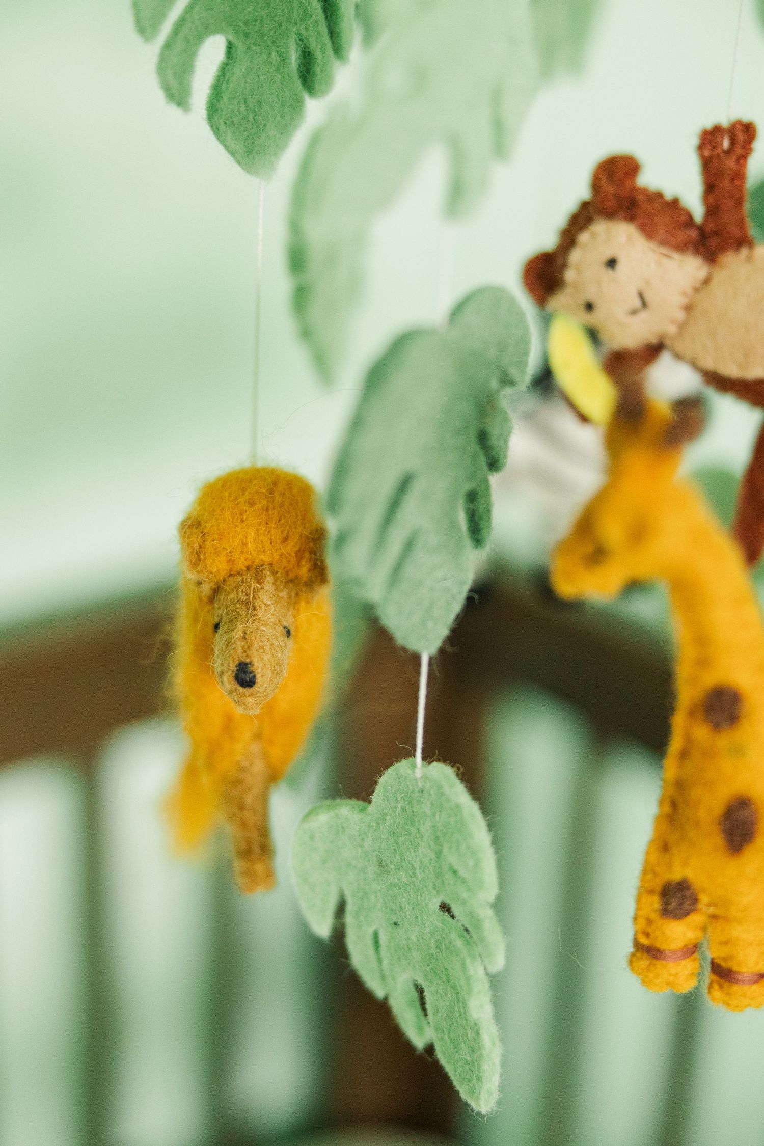 Jungle themed baby mobile with lion and giraffe hanging above crib in a nursery photographed during an in-home newborn session in Palatine