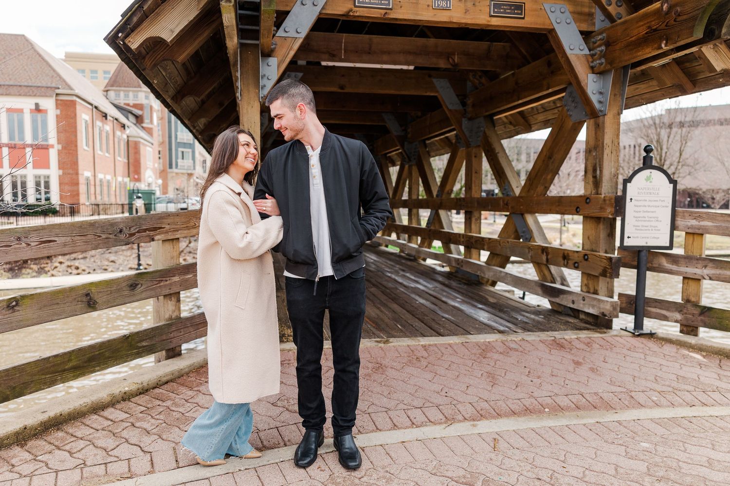 A couple sharing a joyful conversation while standing together on a brick-paved bridge.