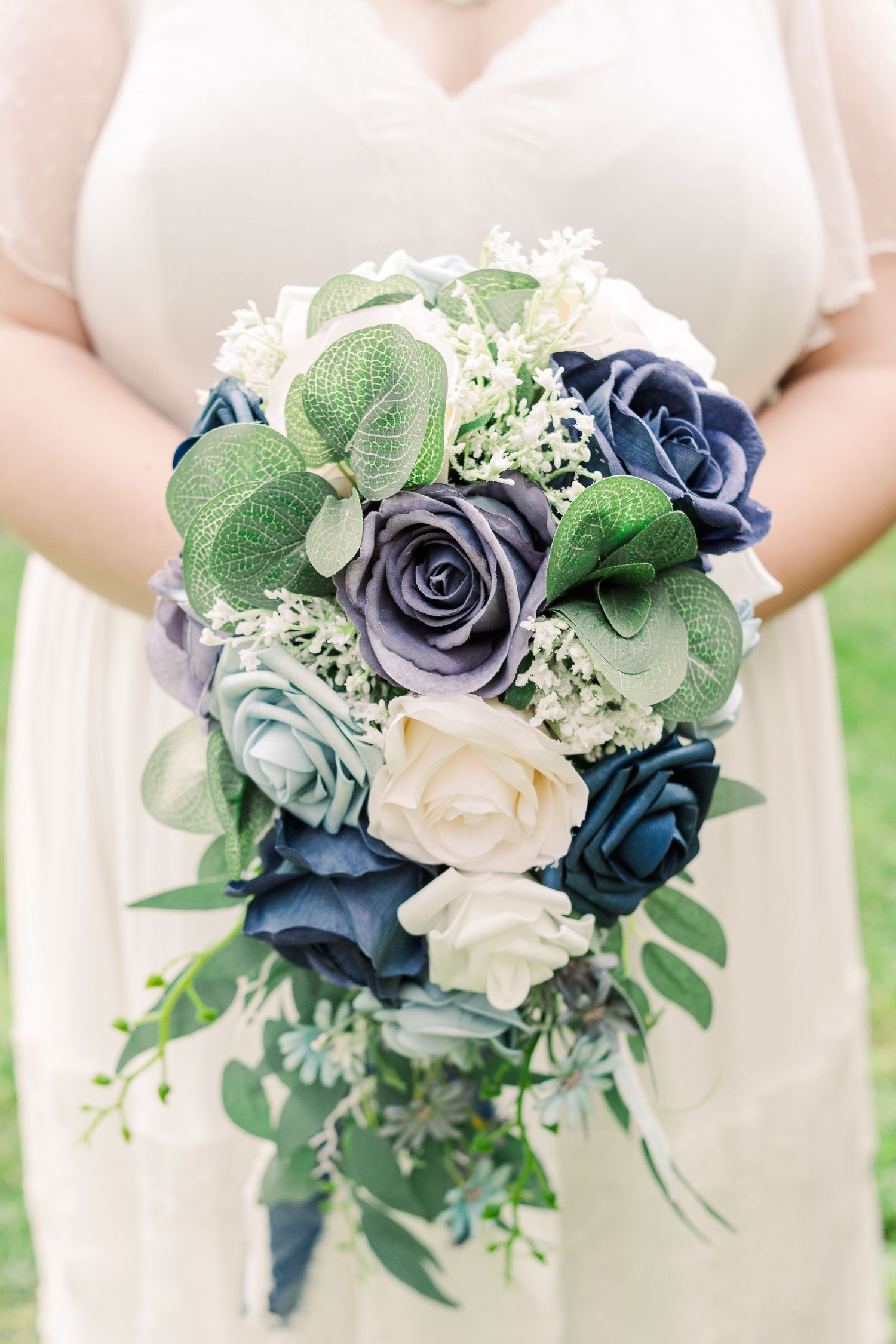 Wedding bouquet featuring navy, light blue and cream roses with green eucalyptus.
