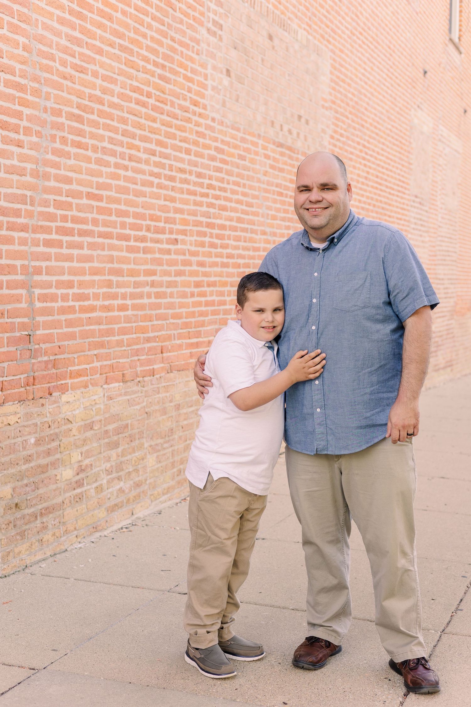 A heartwarming moment captured between two people standing beside a red brick wall.