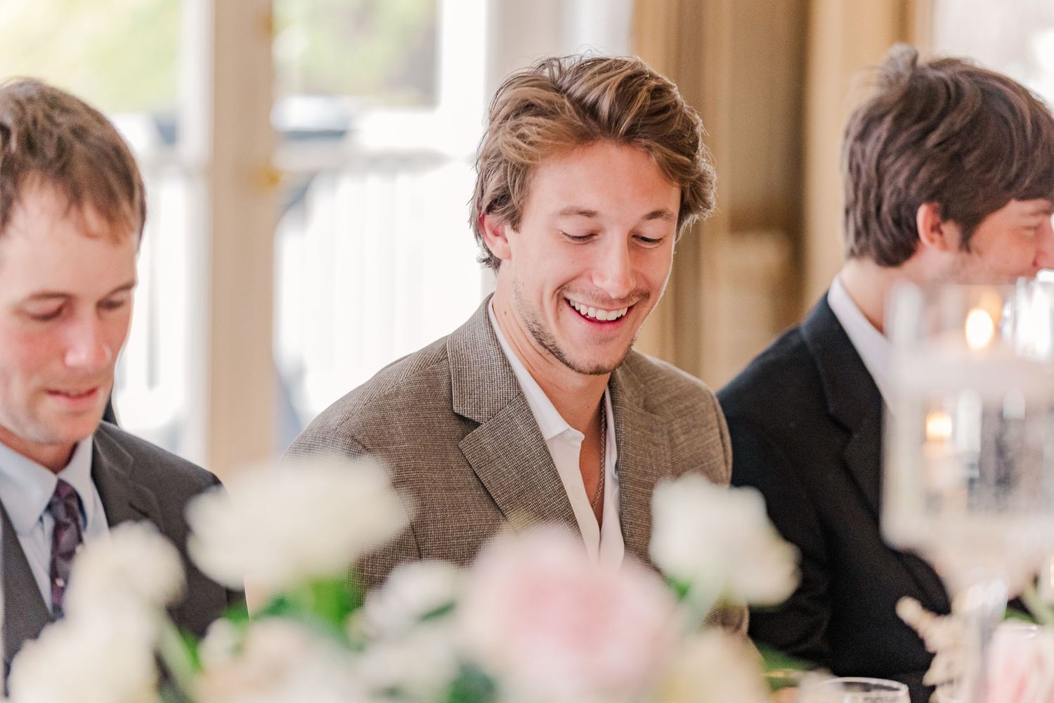 Candid reception photo of guests sharing laughs at elegant wedding dinner.