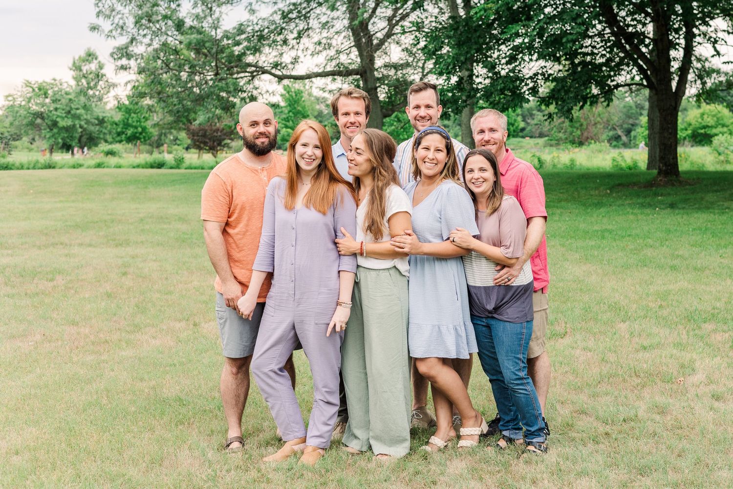 A group of friends and family gathered together for a portrait in a green outdoor setting.