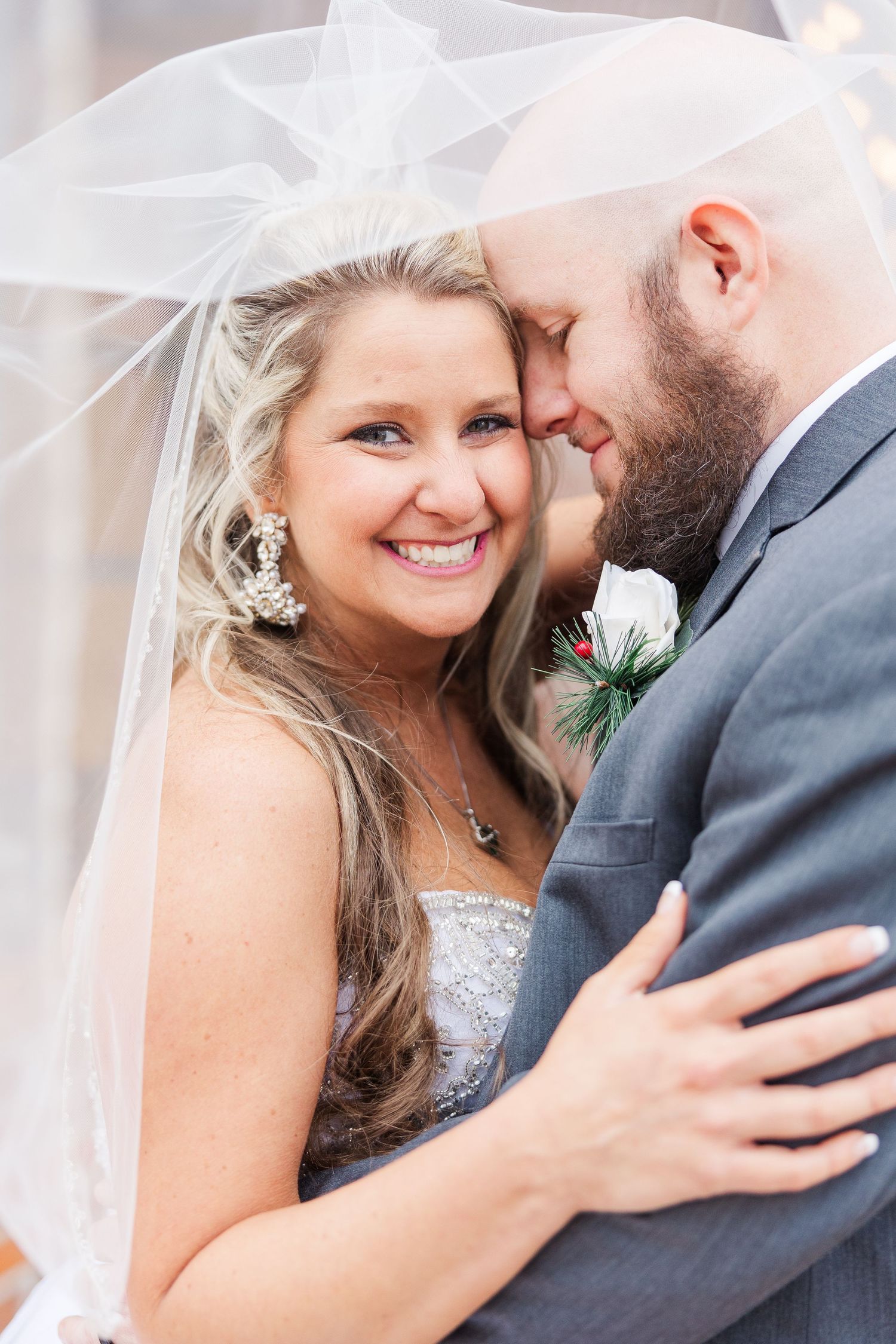 Joyful wedding portrait showing intimate moment under flowing white veil.