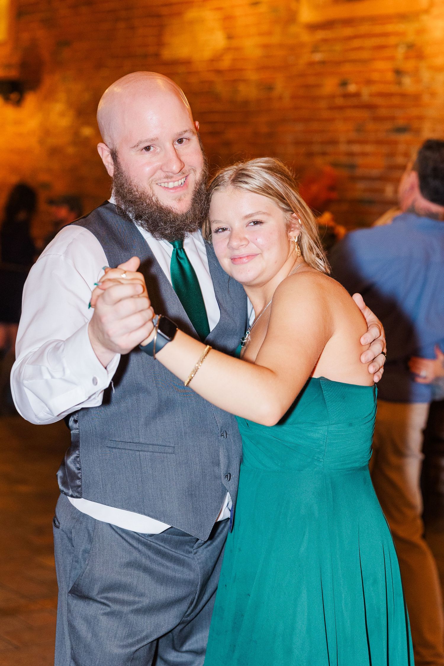 Couple dancing together at wedding reception in rustic brick venue.