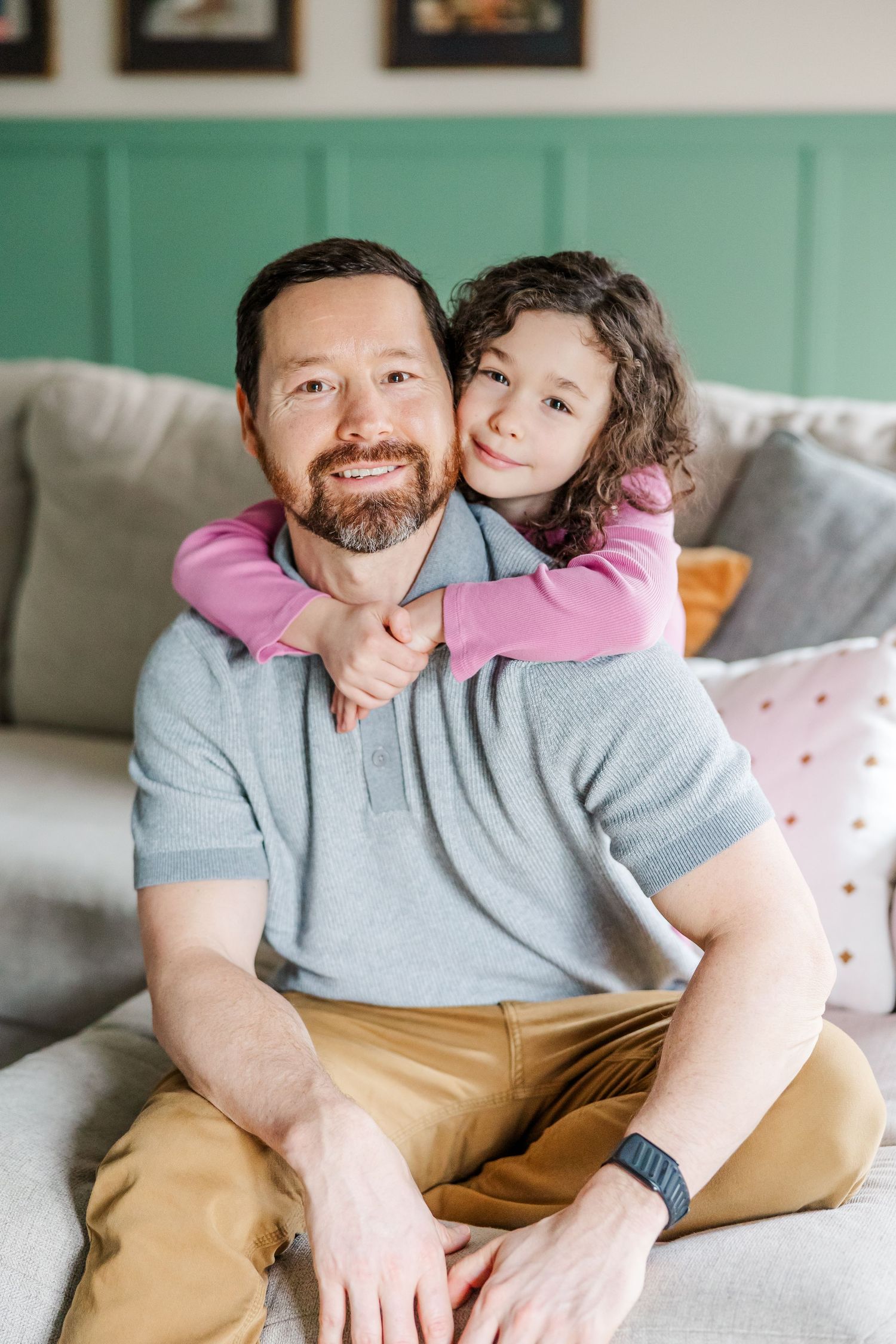 Father and daughter cuddle on couch during in-home lifestyle newborn session in Crystal Lake, Illinois