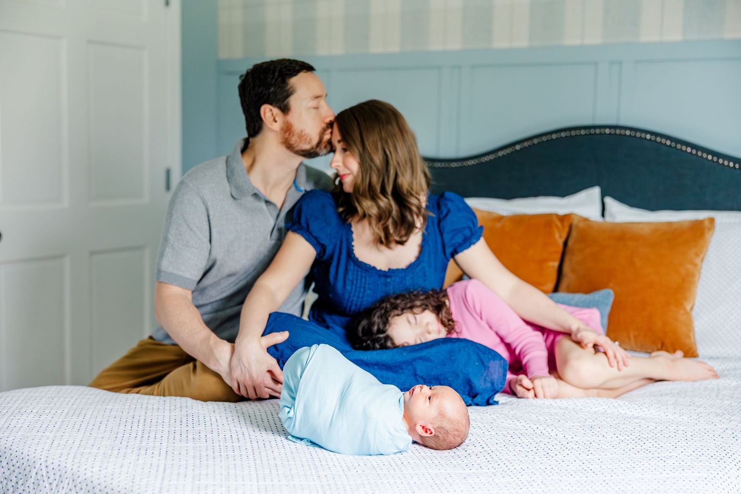 Parents and daughter with newborn on bed during in-home lifestyle newborn session in Crystal Lake, Illinois