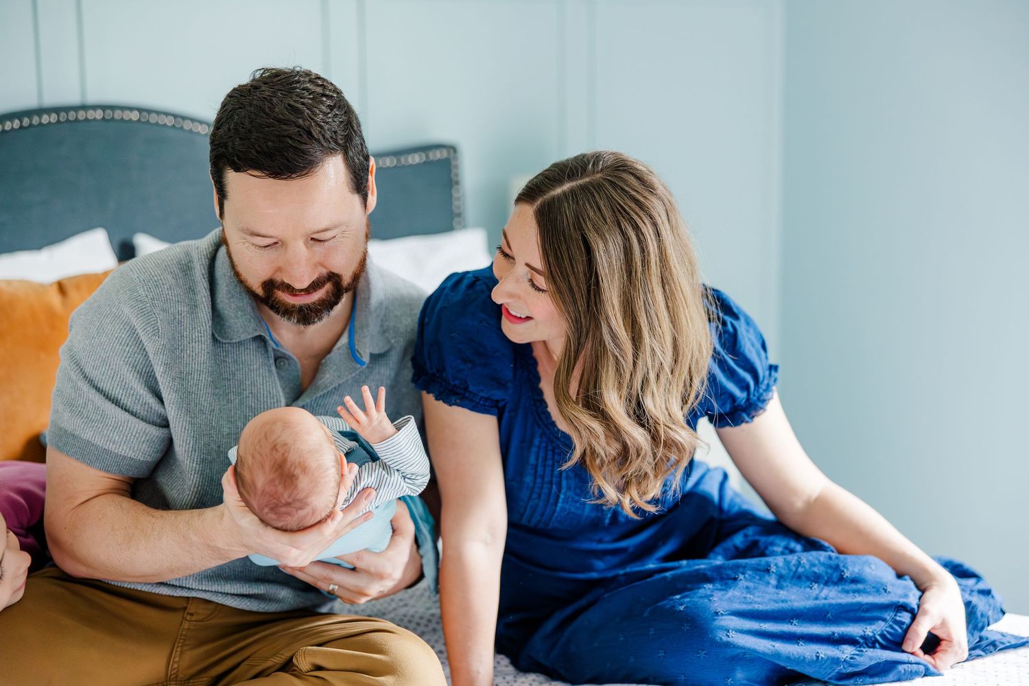 Parents smiling at newborn son on bed during in-home lifestyle newborn session in Crystal Lake, Illinois