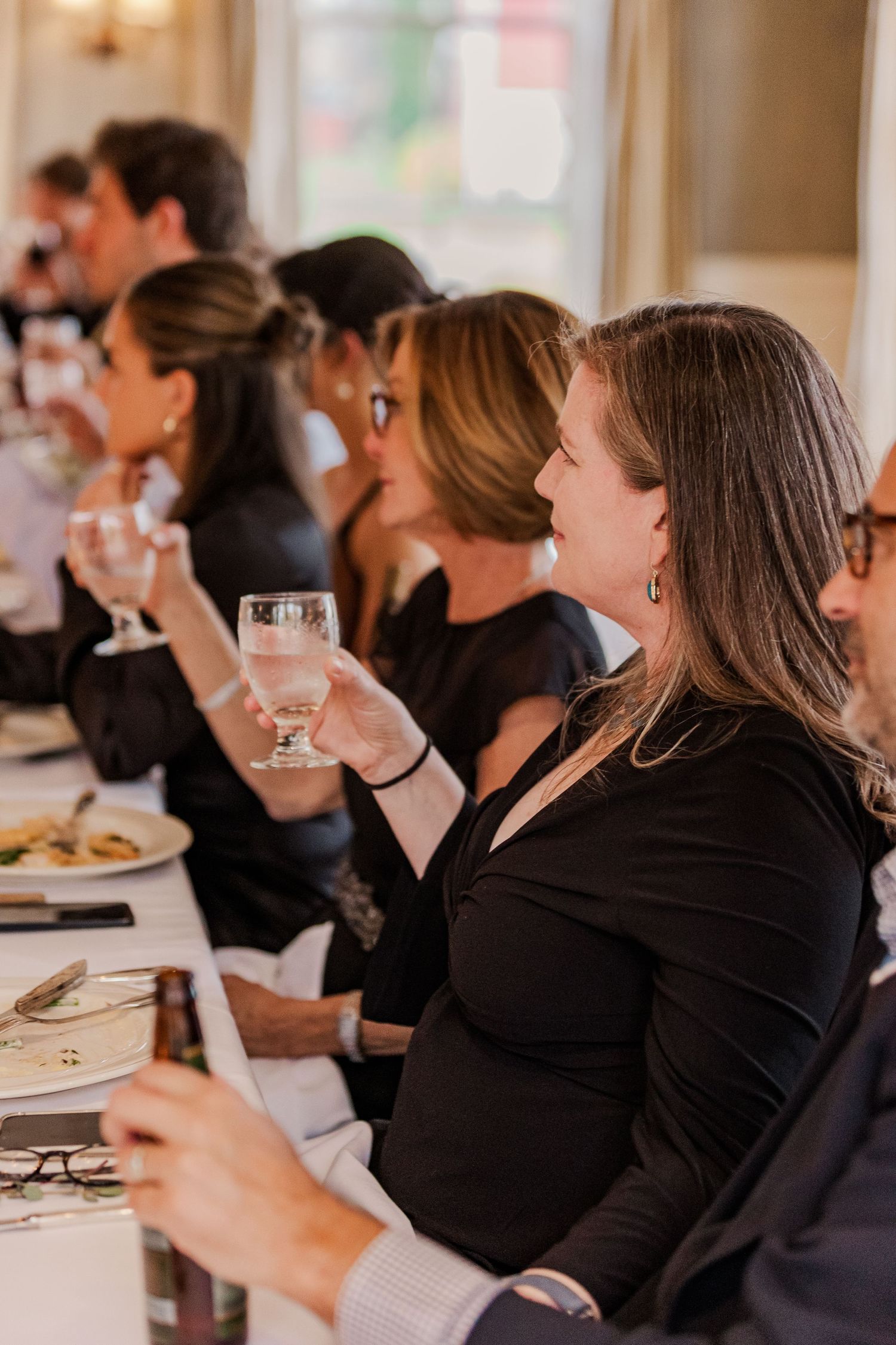 Wedding reception guests seated at long dining table enjoying dinner and conversation.