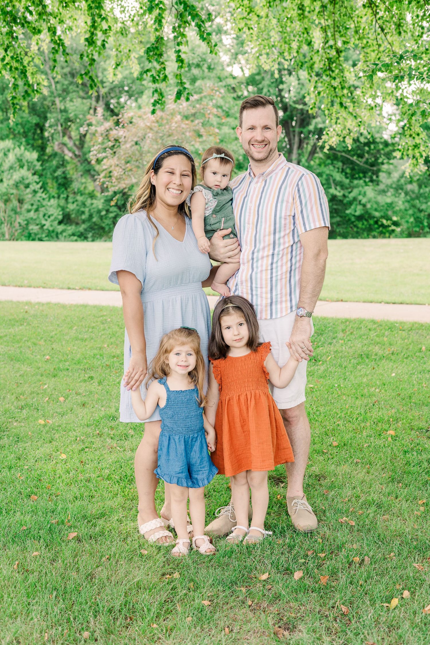 Family of four poses together outdoors wearing coordinated casual outfits.