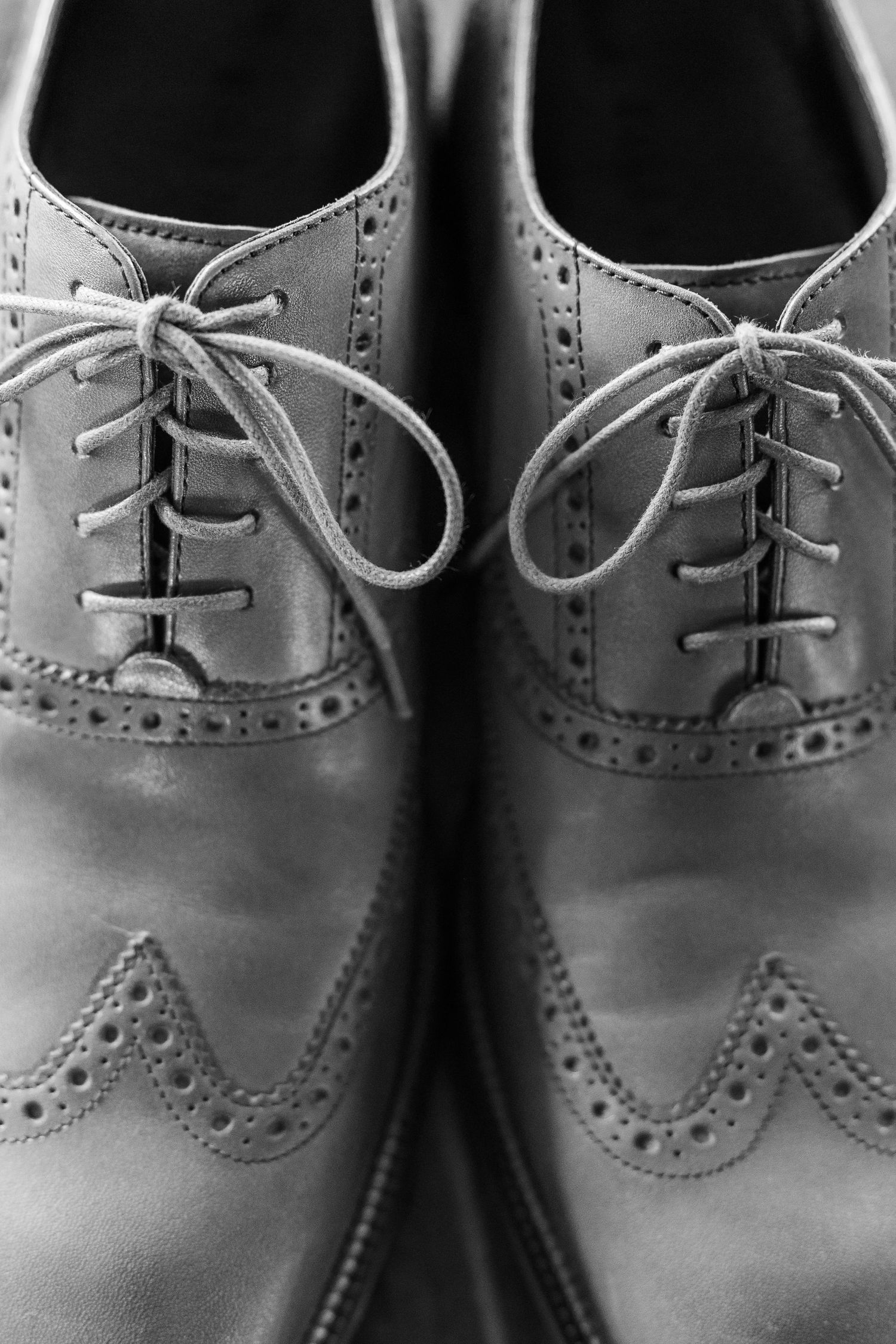Close-up of classic brown leather wingtip oxford dress shoes showing detailed brogue perforations and laces.