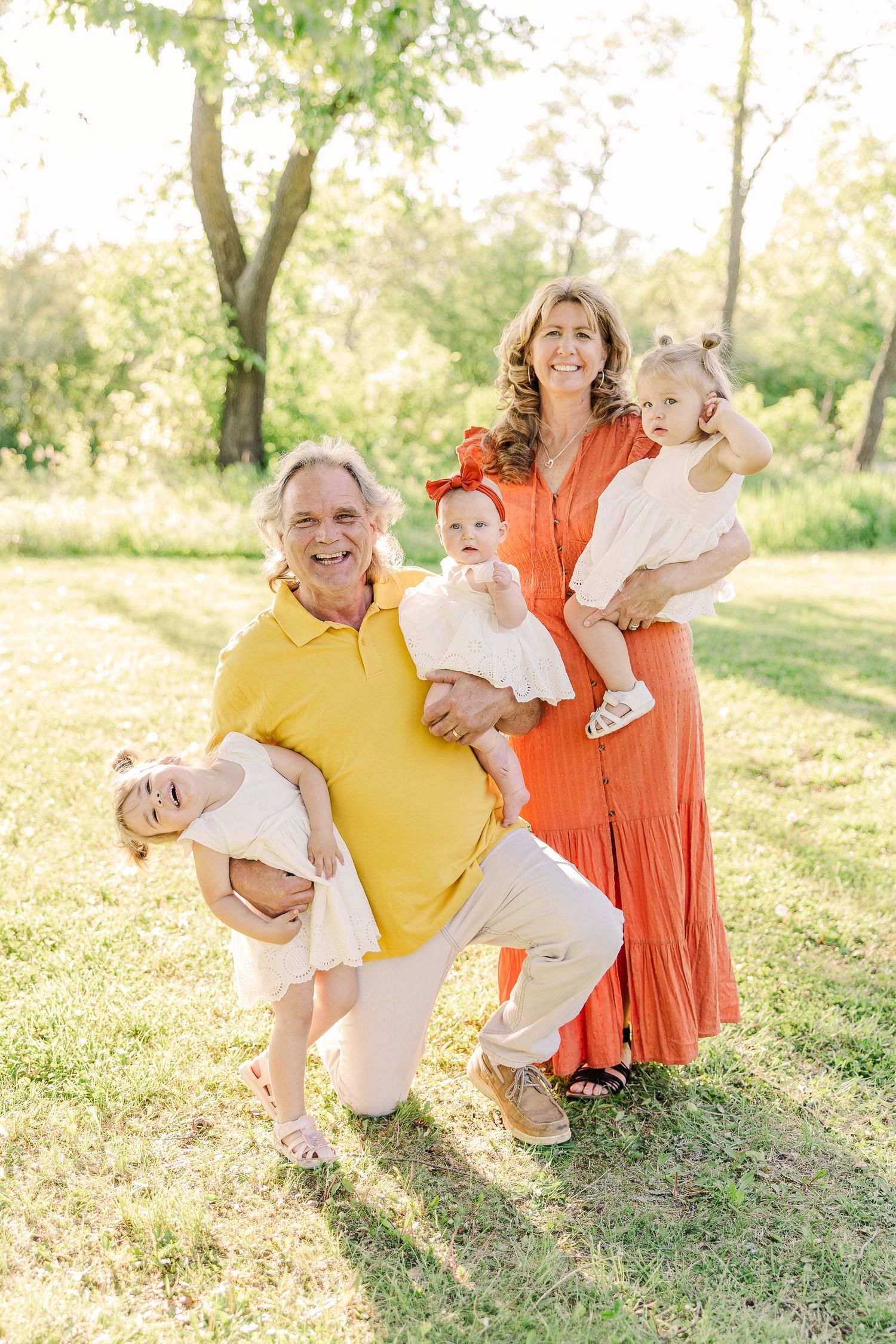 Family of four poses together in sunny outdoor setting wearing yellow and orange outfits.