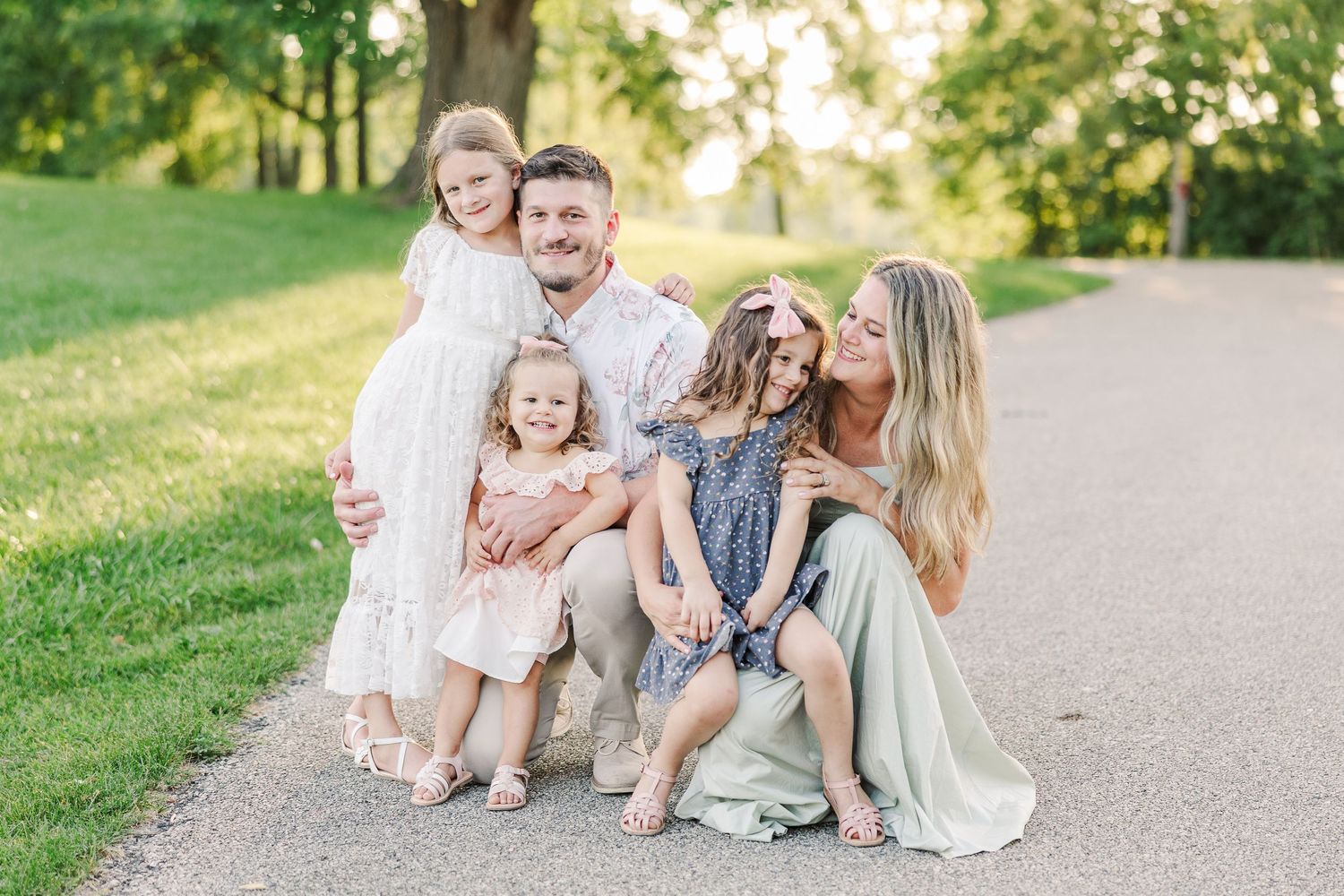 A happy family shares laughter while posing together on a path during golden hour.