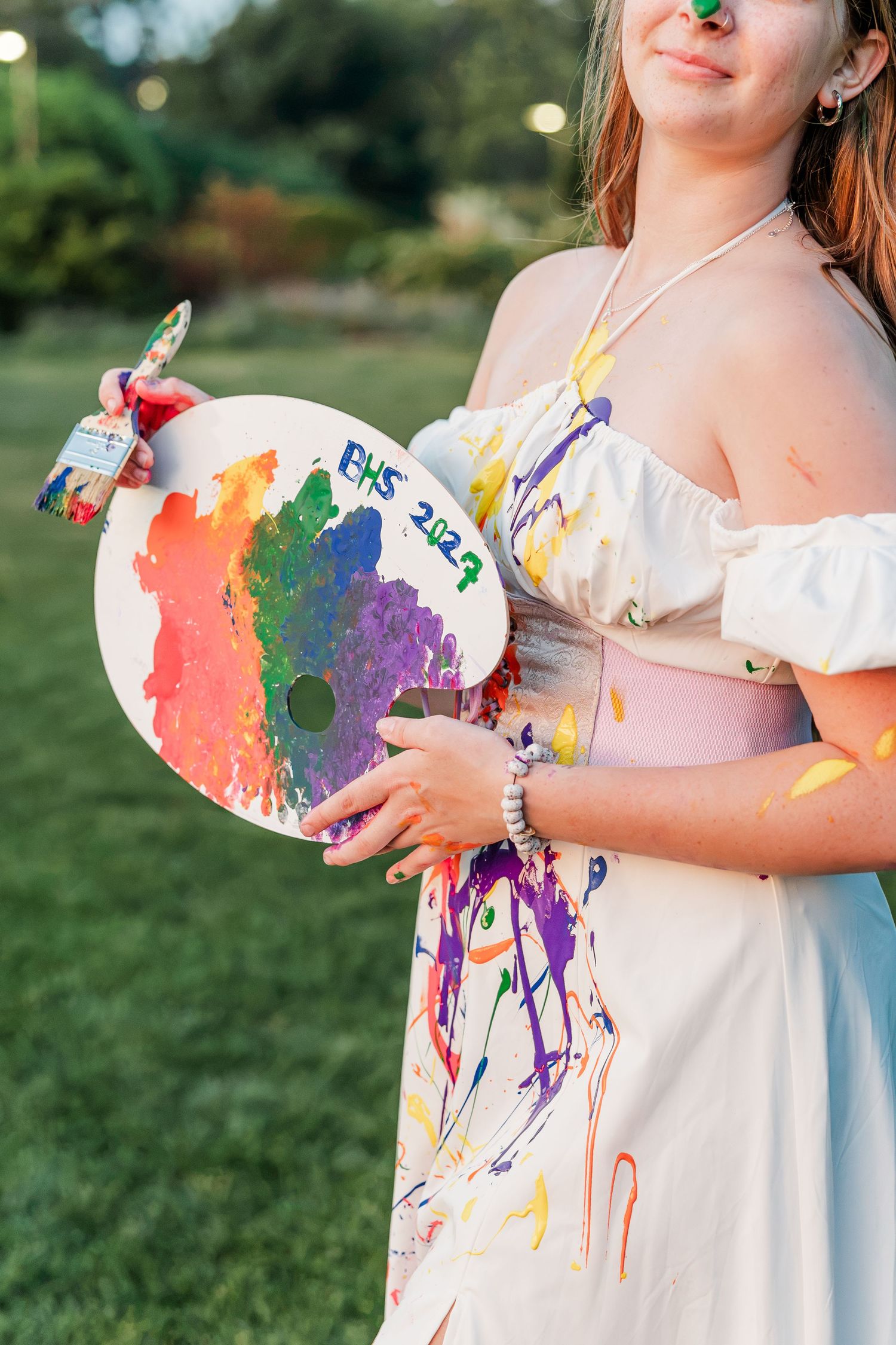 Samantha holds her colorful BHS 2027 palette while wearing her paint-covered dress during her creative senior portraits.