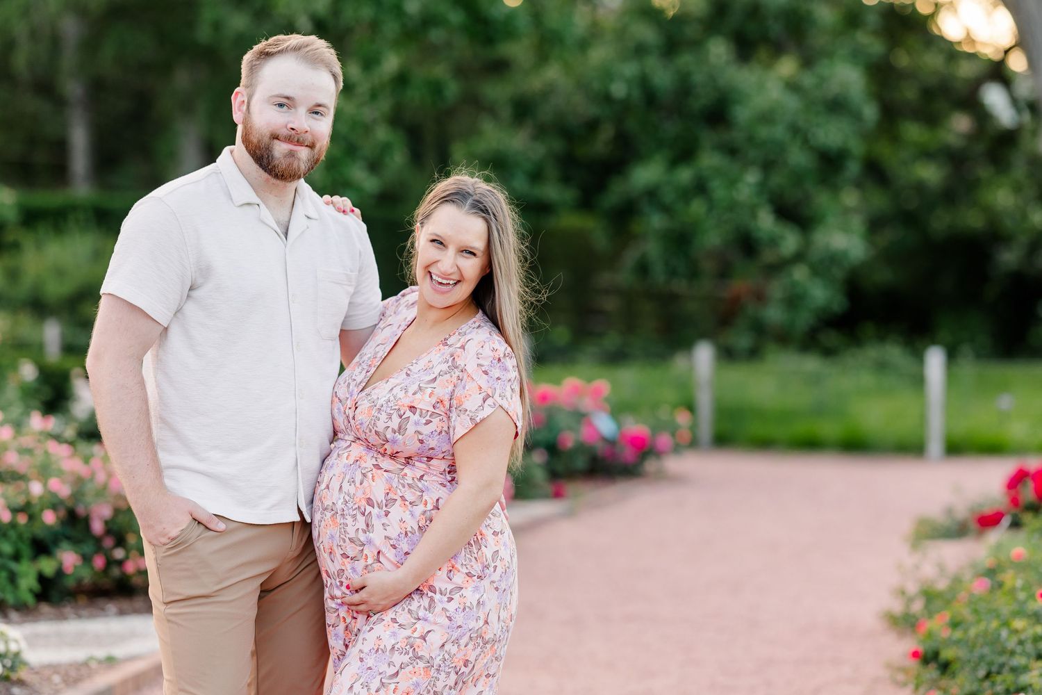 Smiling expecting mother in a floral dress during a summer maternity session at Cantigny Park in Wheaton Illinois