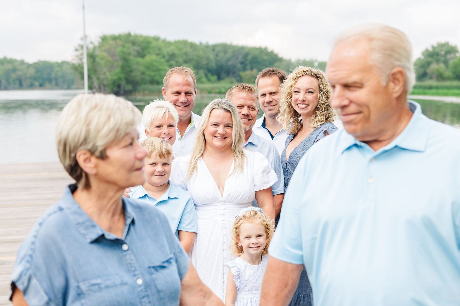 Family gathering on a lakeside dock with people smiling and enjoying each other's company.