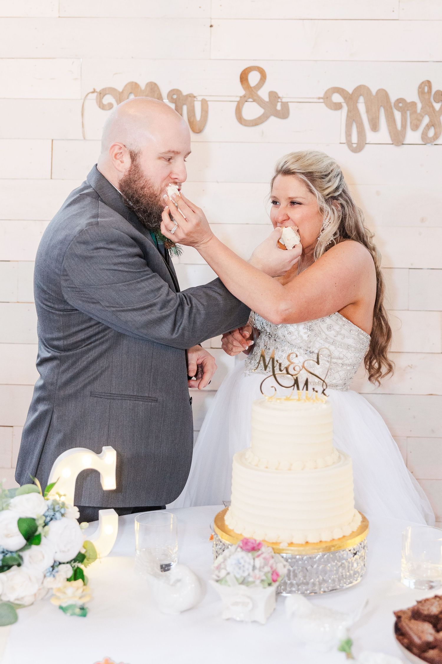 Wedding couple playfully feeding each other cake at their reception.