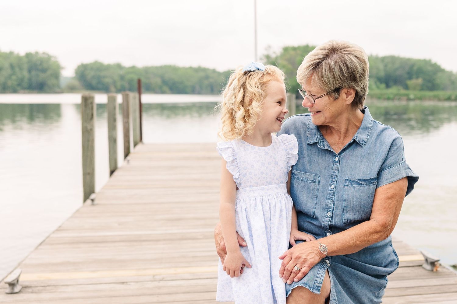 A touching moment between two people sharing conversation on a lakeside dock.