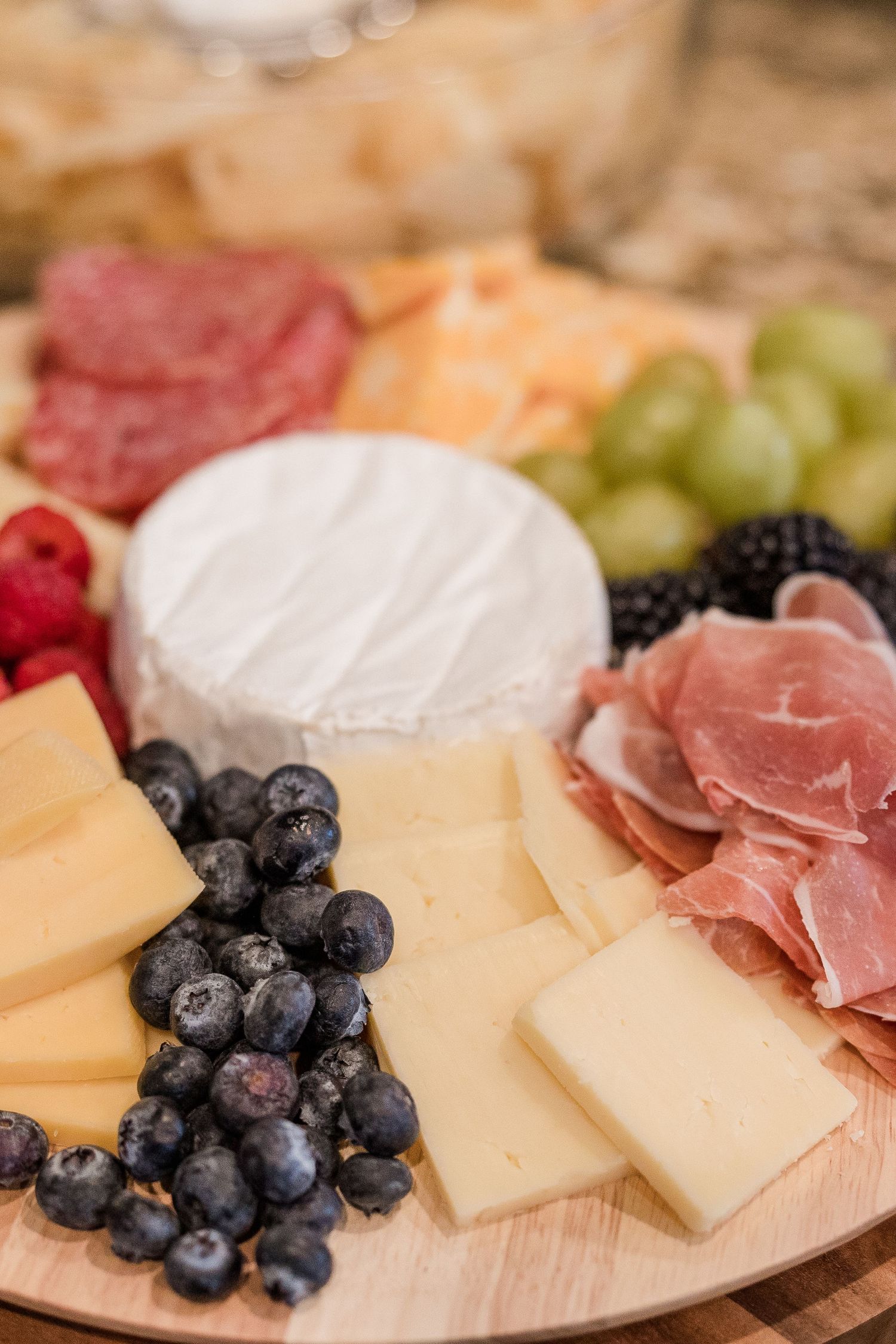 Close-up of gourmet cheese board with fresh berries, cured meats, and assorted cheeses.