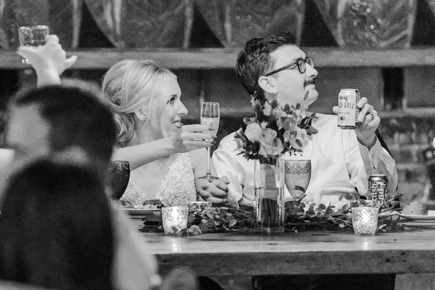 Black and white photo of guests sharing animated conversation at wedding reception.