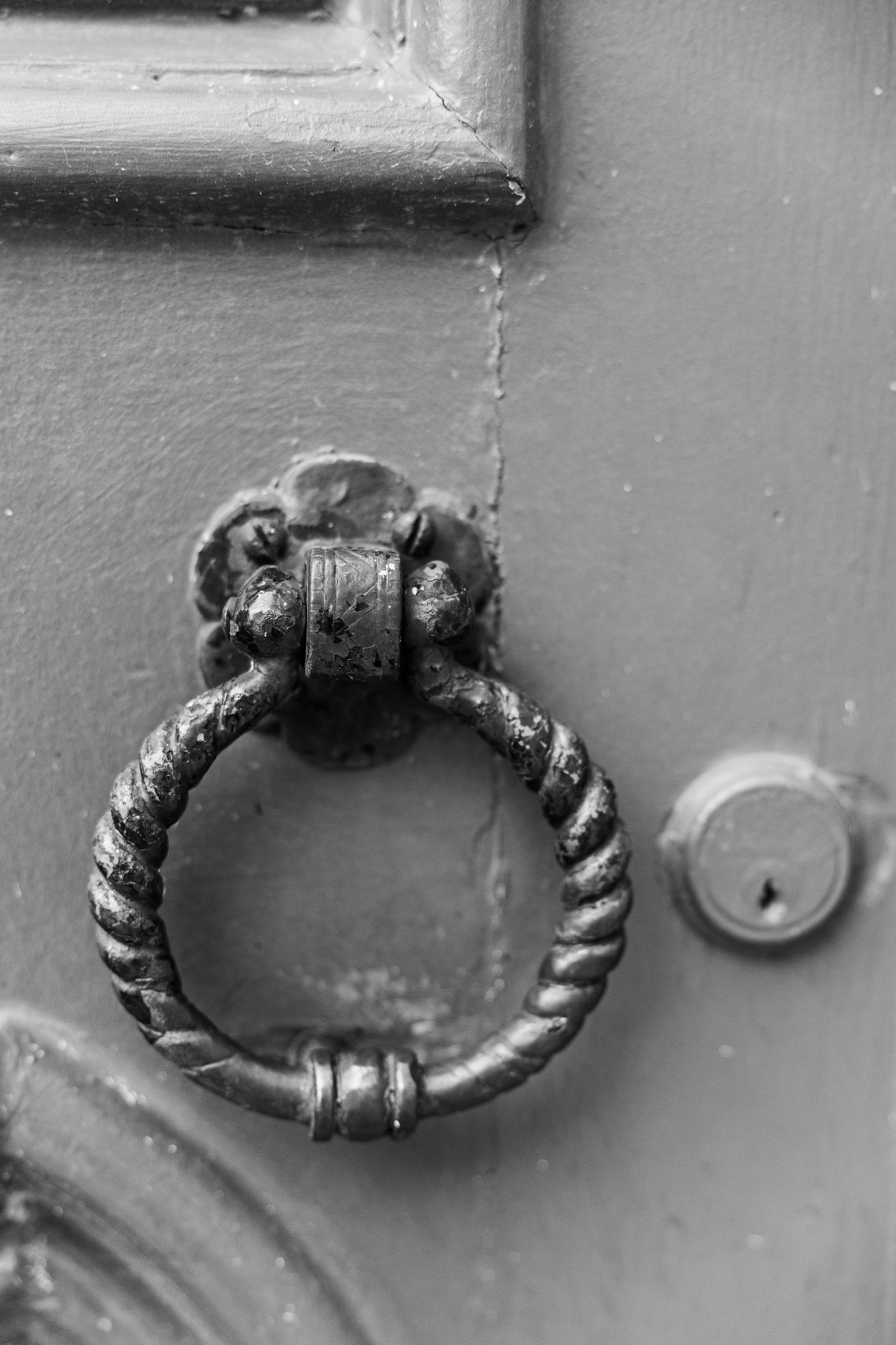 Close-up of an antique wrought iron door knocker ring mounted on a gray door.