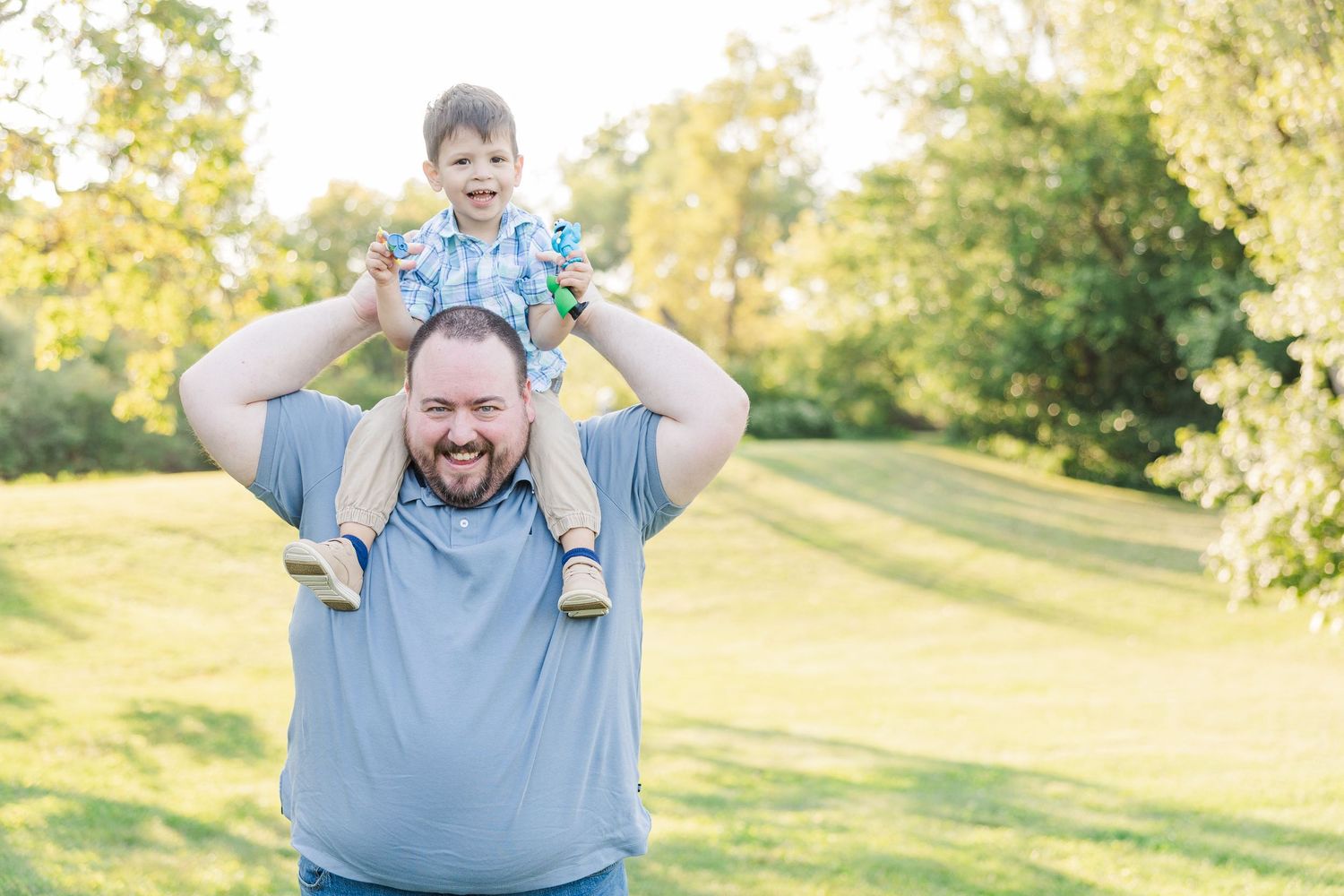 A sequence of figures enjoying time together outdoors in a sunny green park setting.Sorg family portraits at Shamrock Hills Park in Crystal