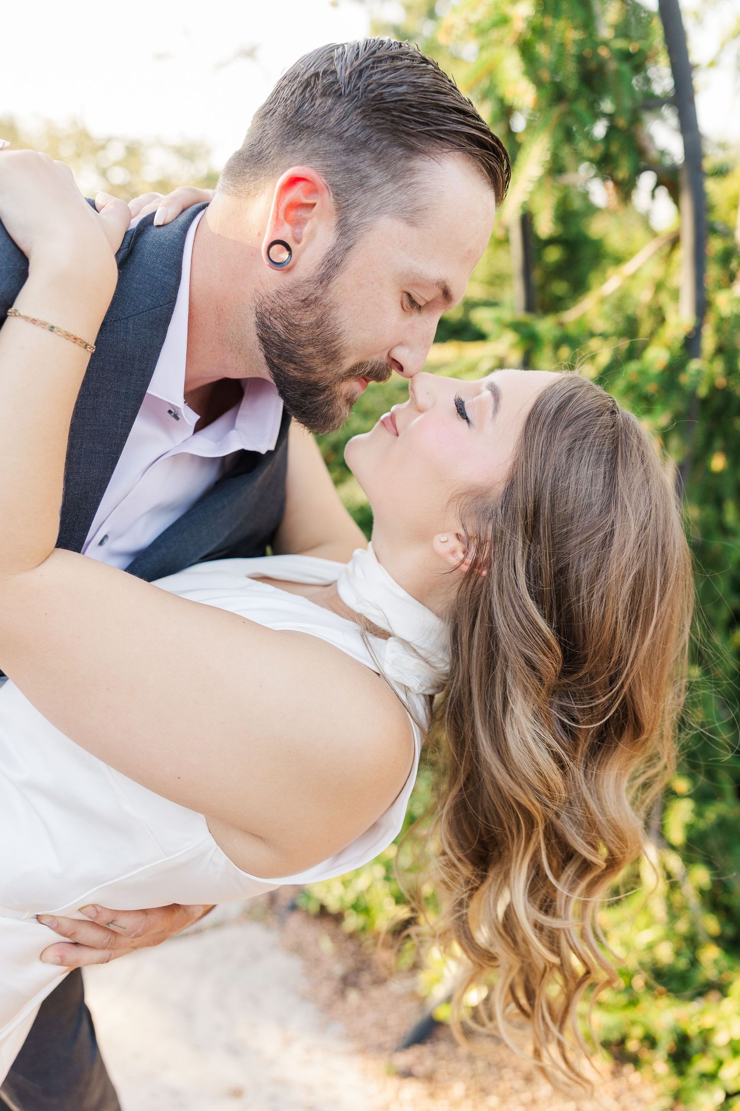 Couple kissing beneath garden arch during engagement photos at Cantigny Park