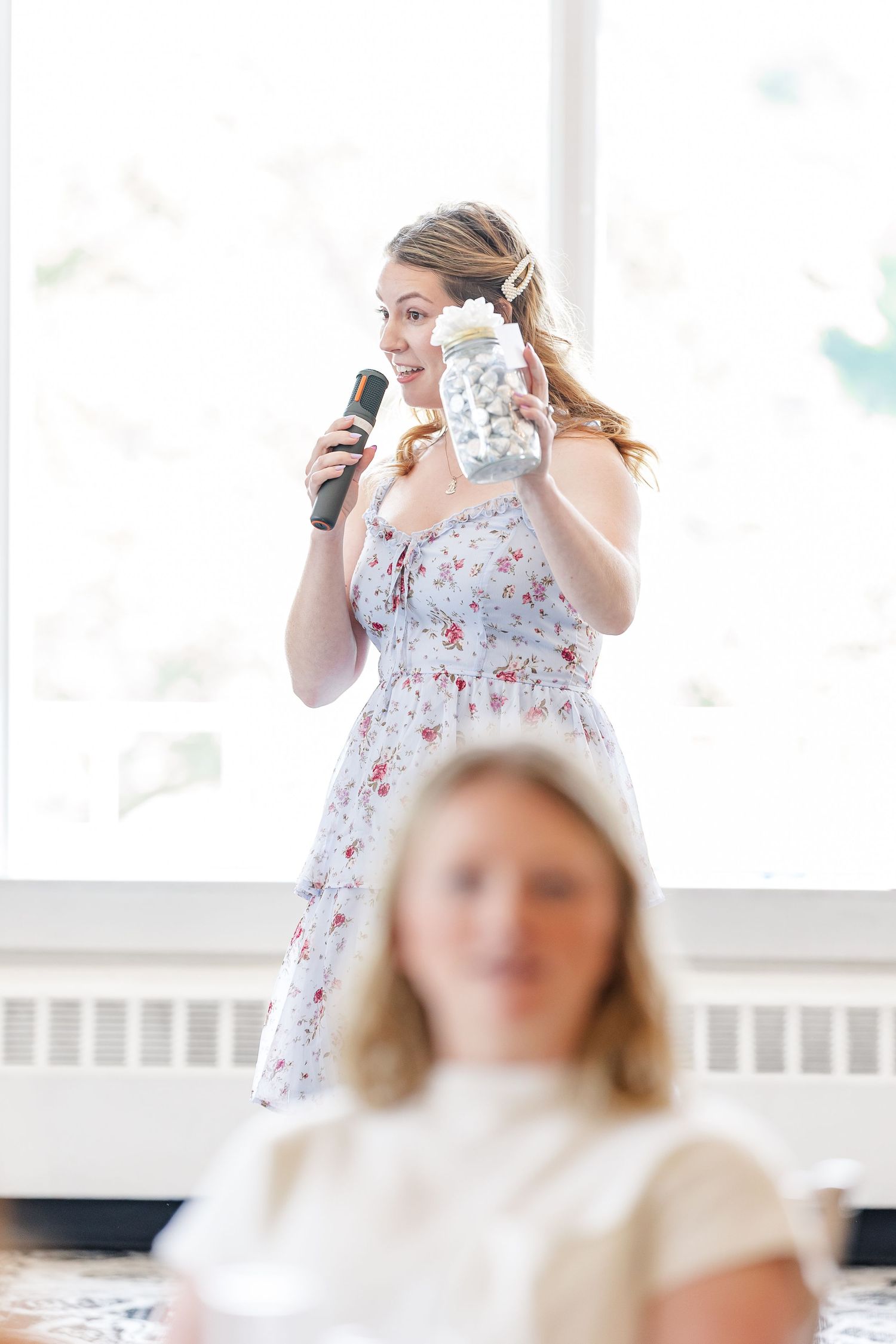 Bridesmaid giving a toast with microphone at Sarah's bridal shower