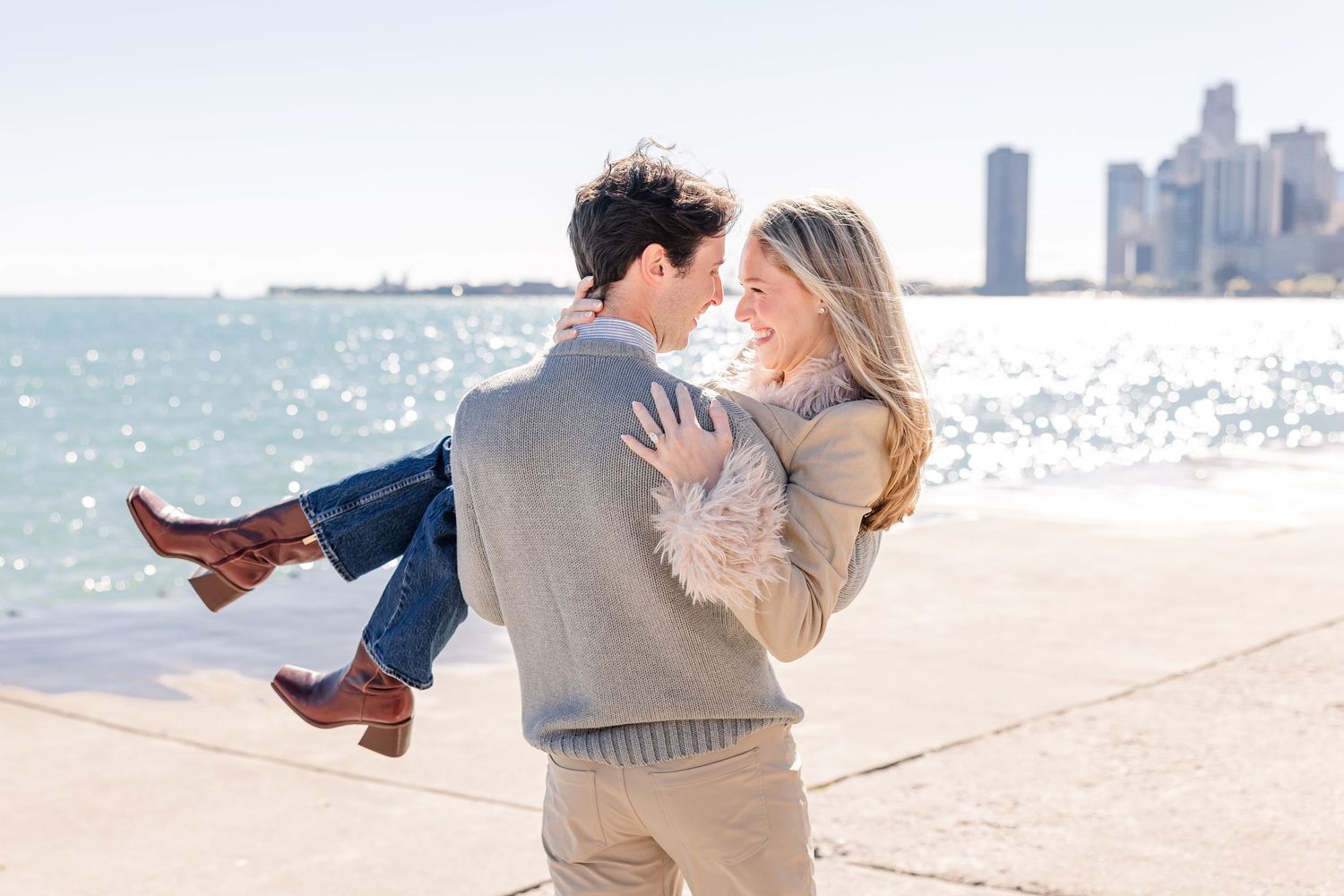 Couple sharing a romantic moment by the waterfront, man lifting woman with Chicago skyline in the background.