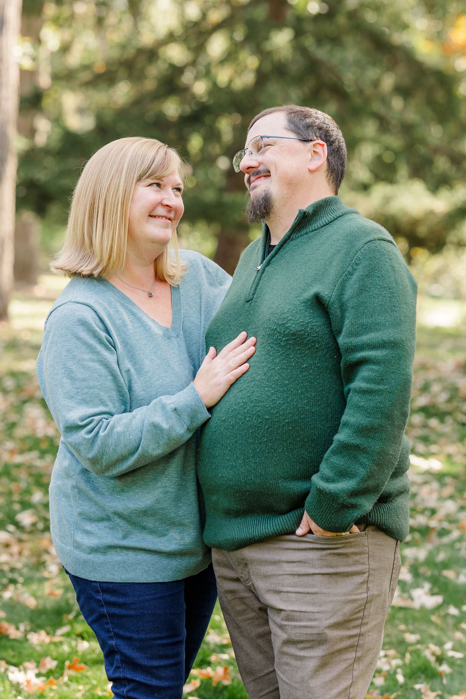 Happy middle-aged couple laughs together in a lush green park in fall.