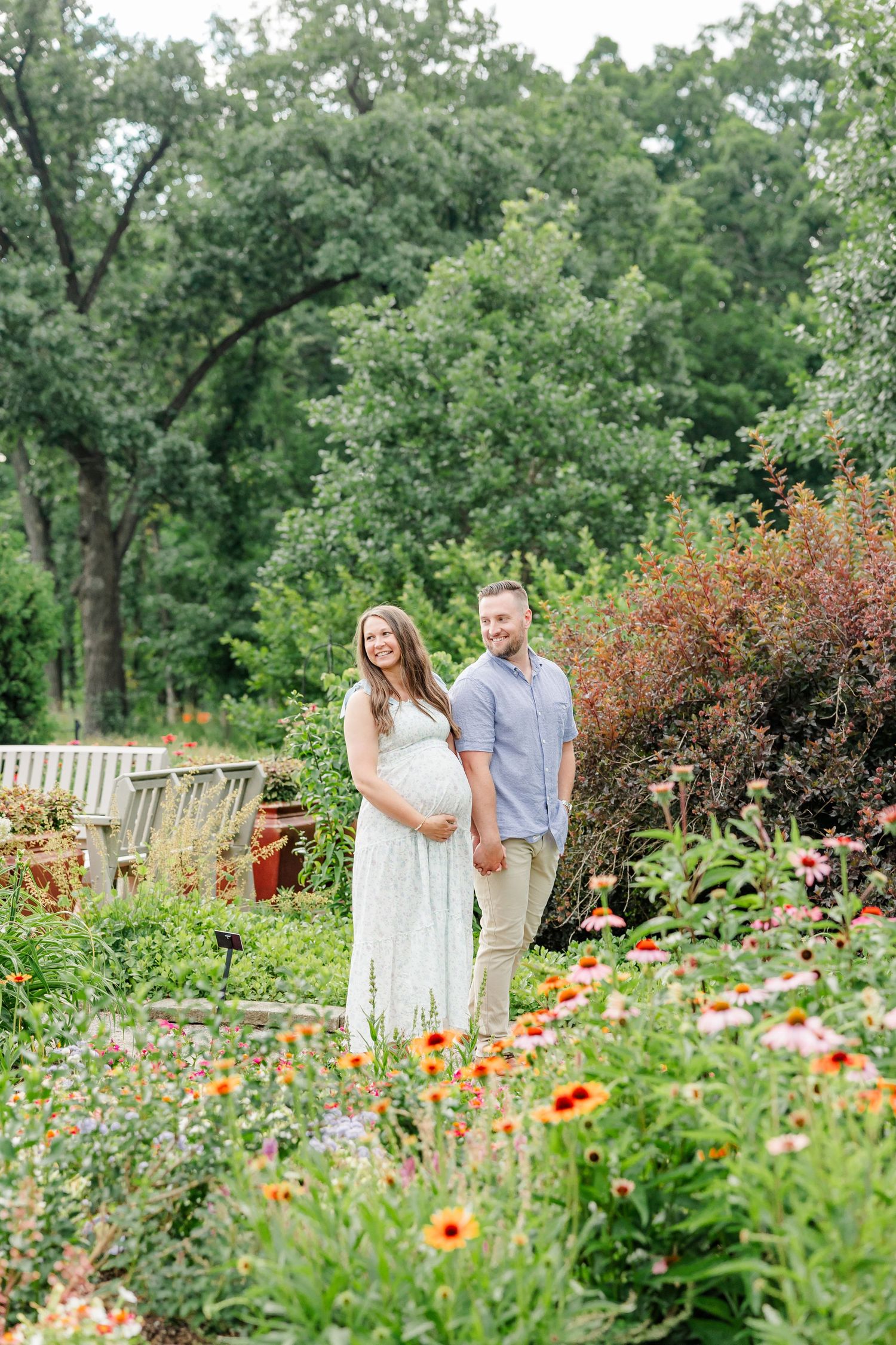 Expecting parents surrounded by colorful summer flowers at Cantigny Park
