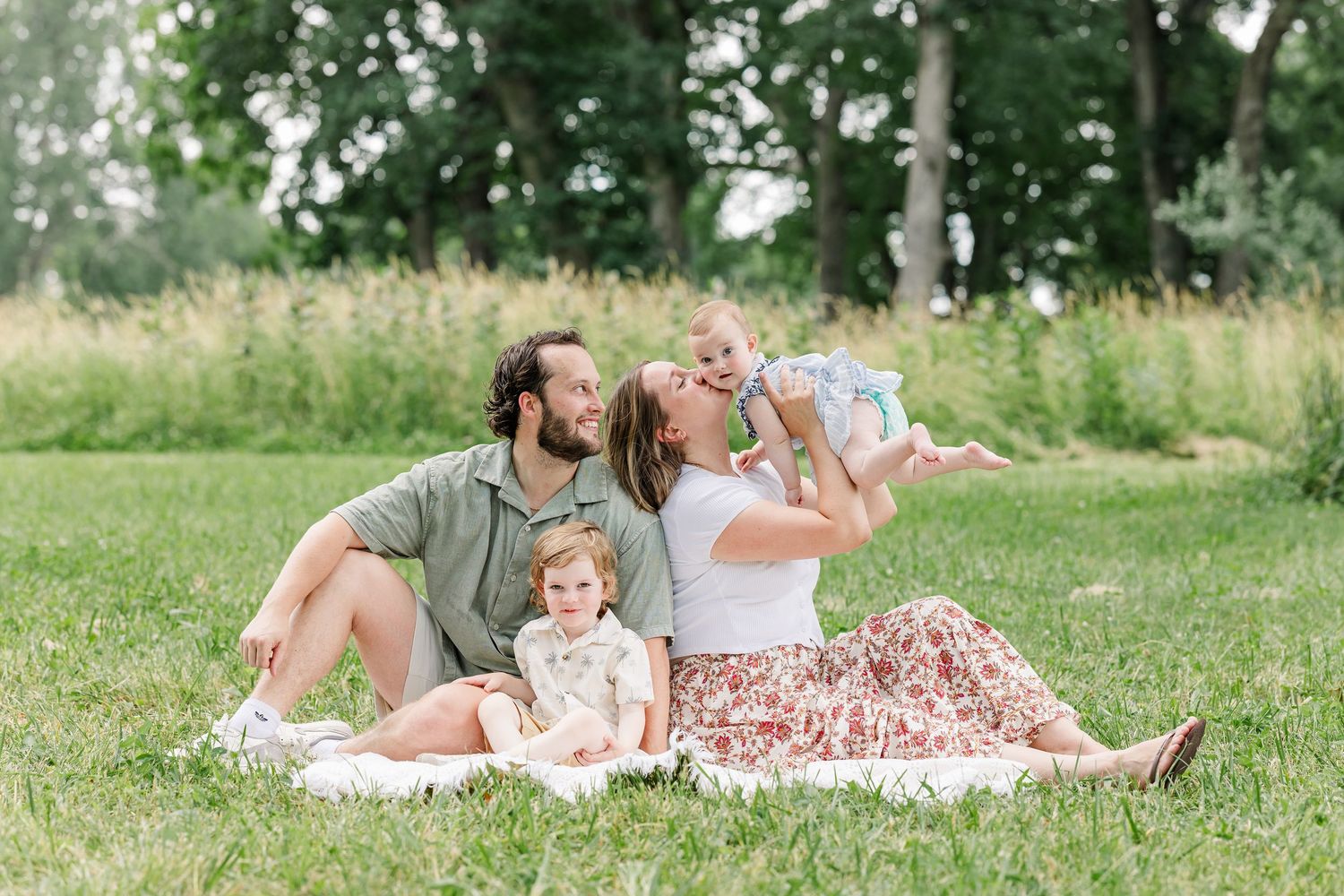Family cuddling on a blanket during a summer extended family session in Crystal Lake, Illinois.