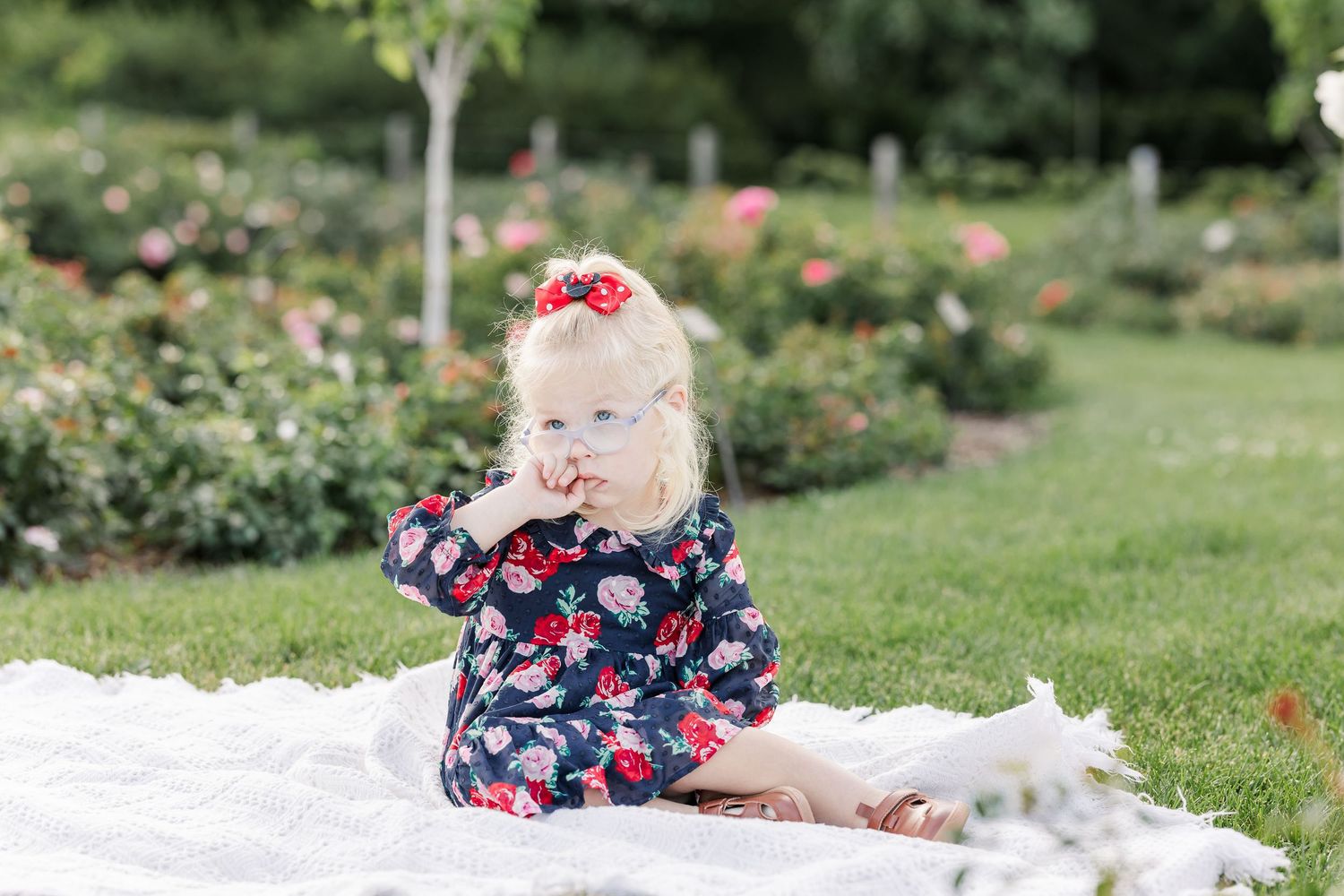 Caroline smiling while sitting on a white blanket surrounded by the gardens at Cantigny Park.