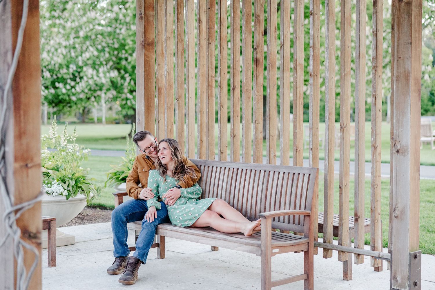Romantic engagement photo of a couple cuddling on a bench at Cantigny Park in Wheaton