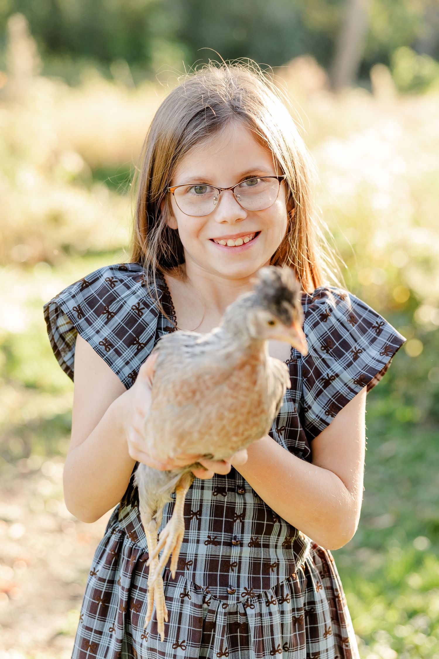 Smiling girl holding a chicken during fall family photos at home in St. Charles, IL.