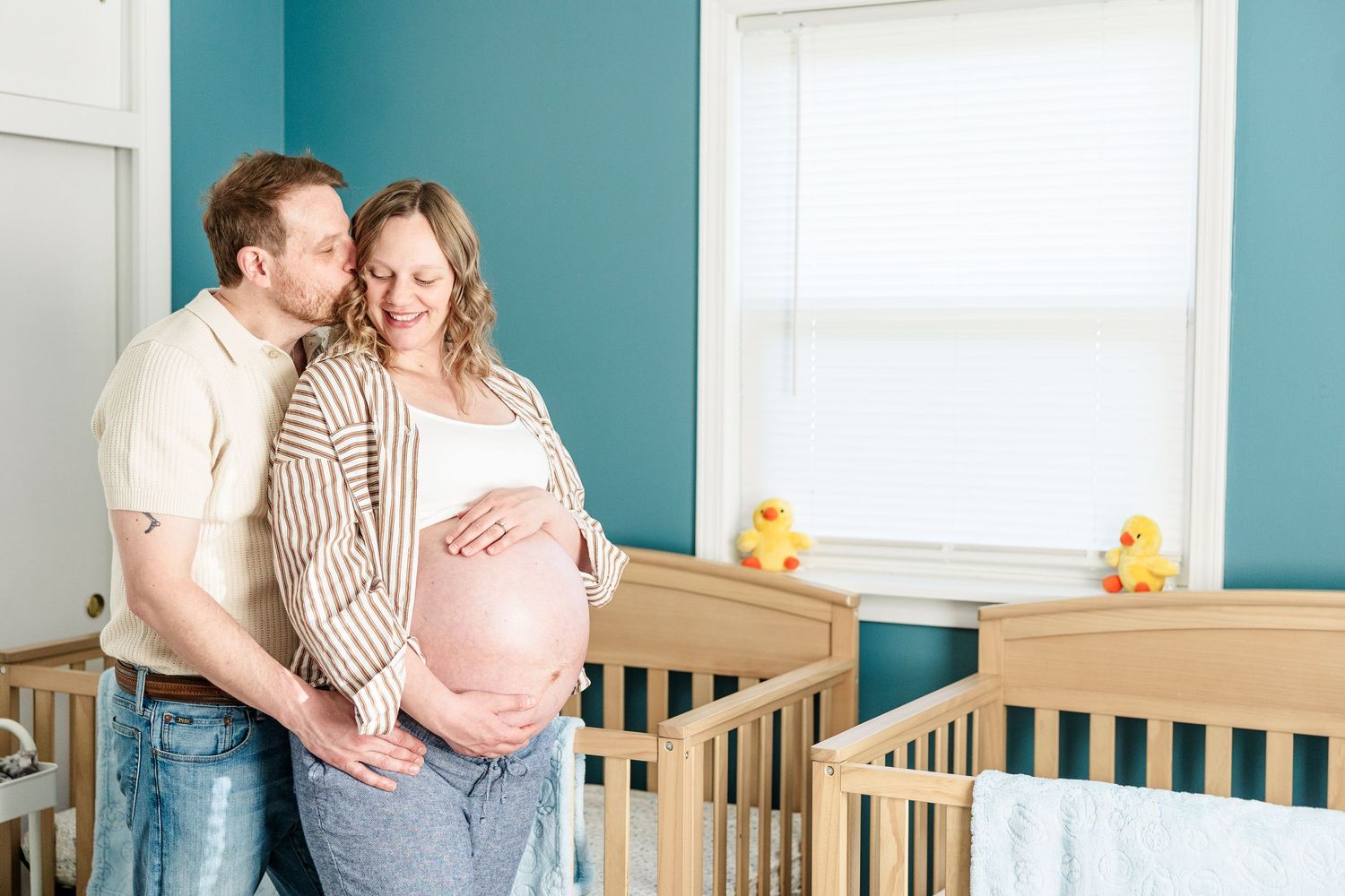 Expecting parents smiling together in twin boys’ nursery during an in-home maternity session in Crystal Lake.