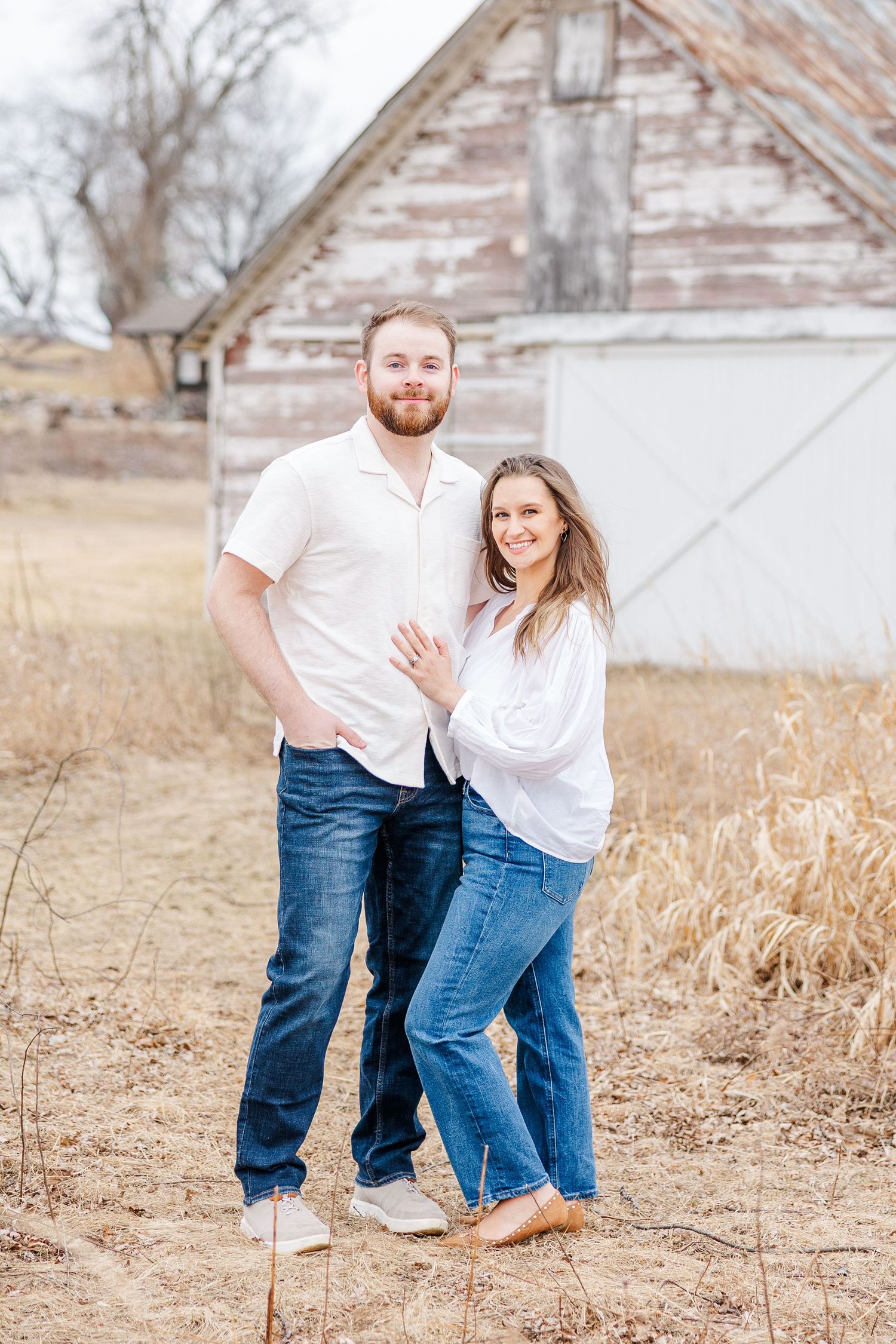 Couple posing by rustic barn during pregnancy announcement photos in Cary, Illinois