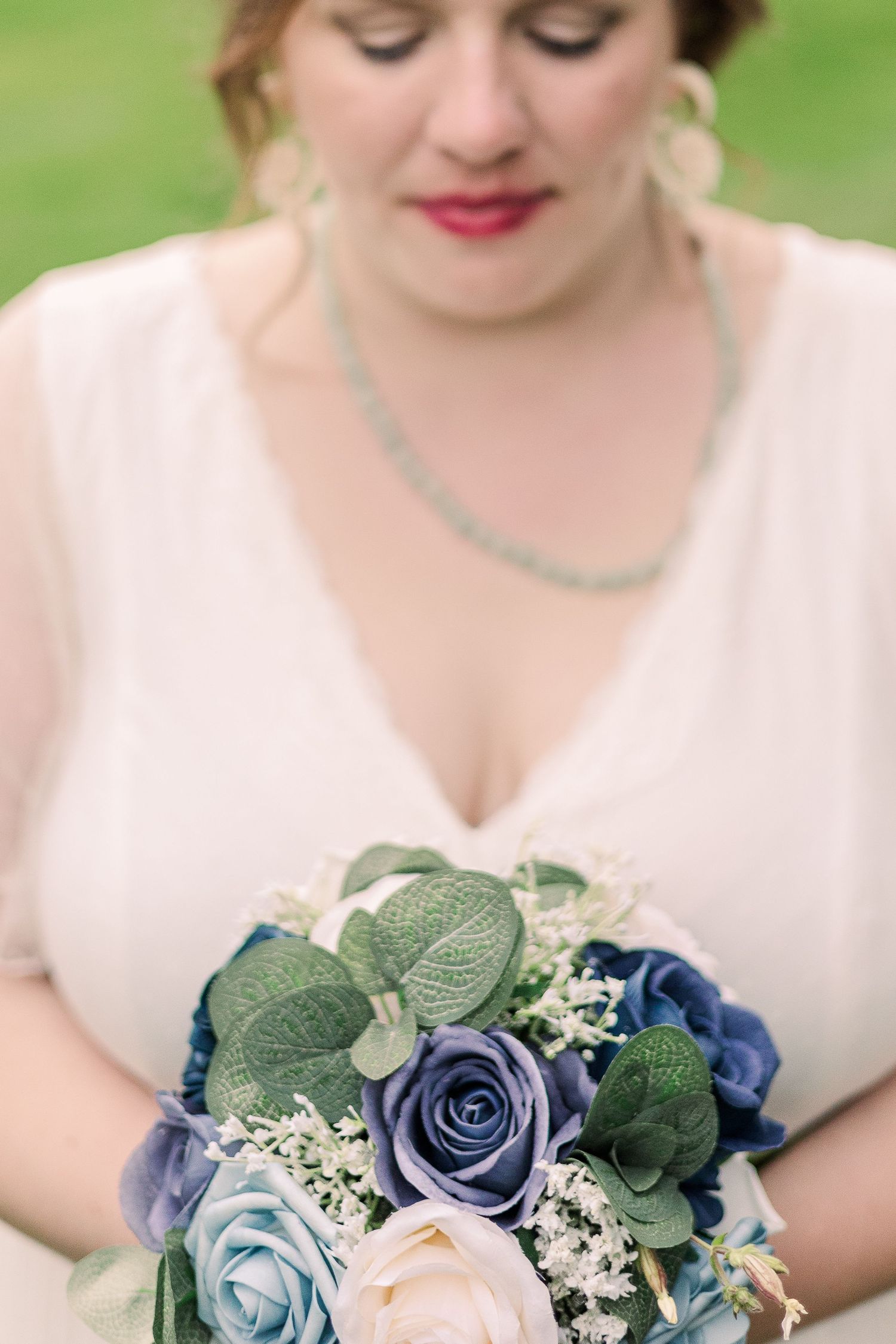Close-up of bridal bouquet featuring blue and pink roses with greenery.