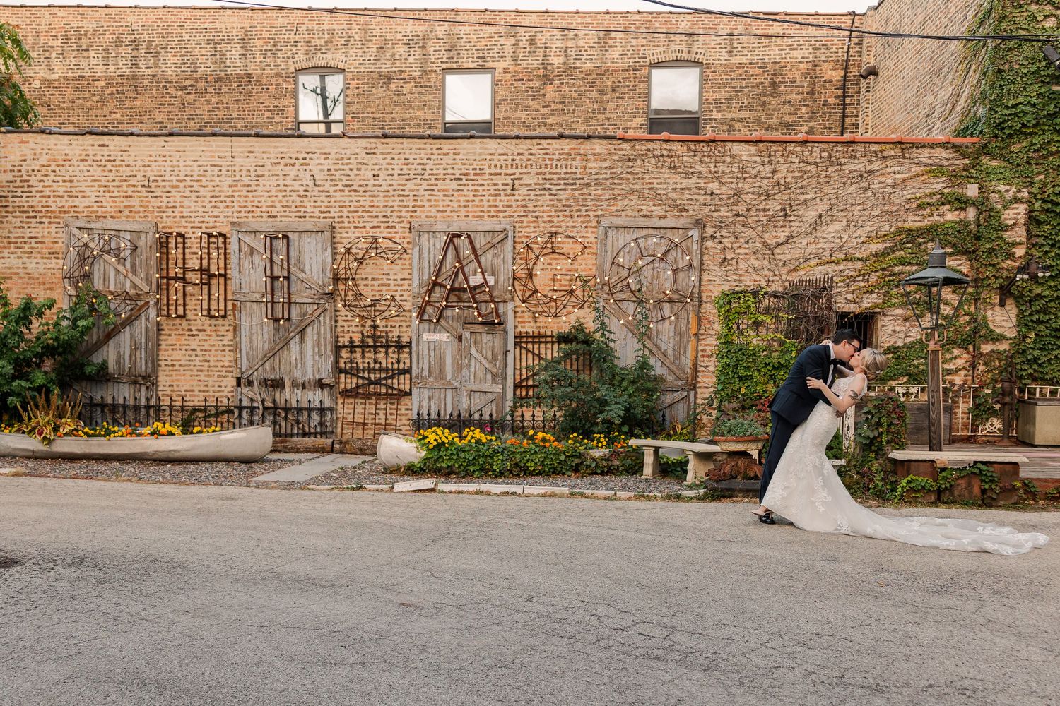 A wedding couple embracing against a brick wall with urban graffiti art in an industrial setting.