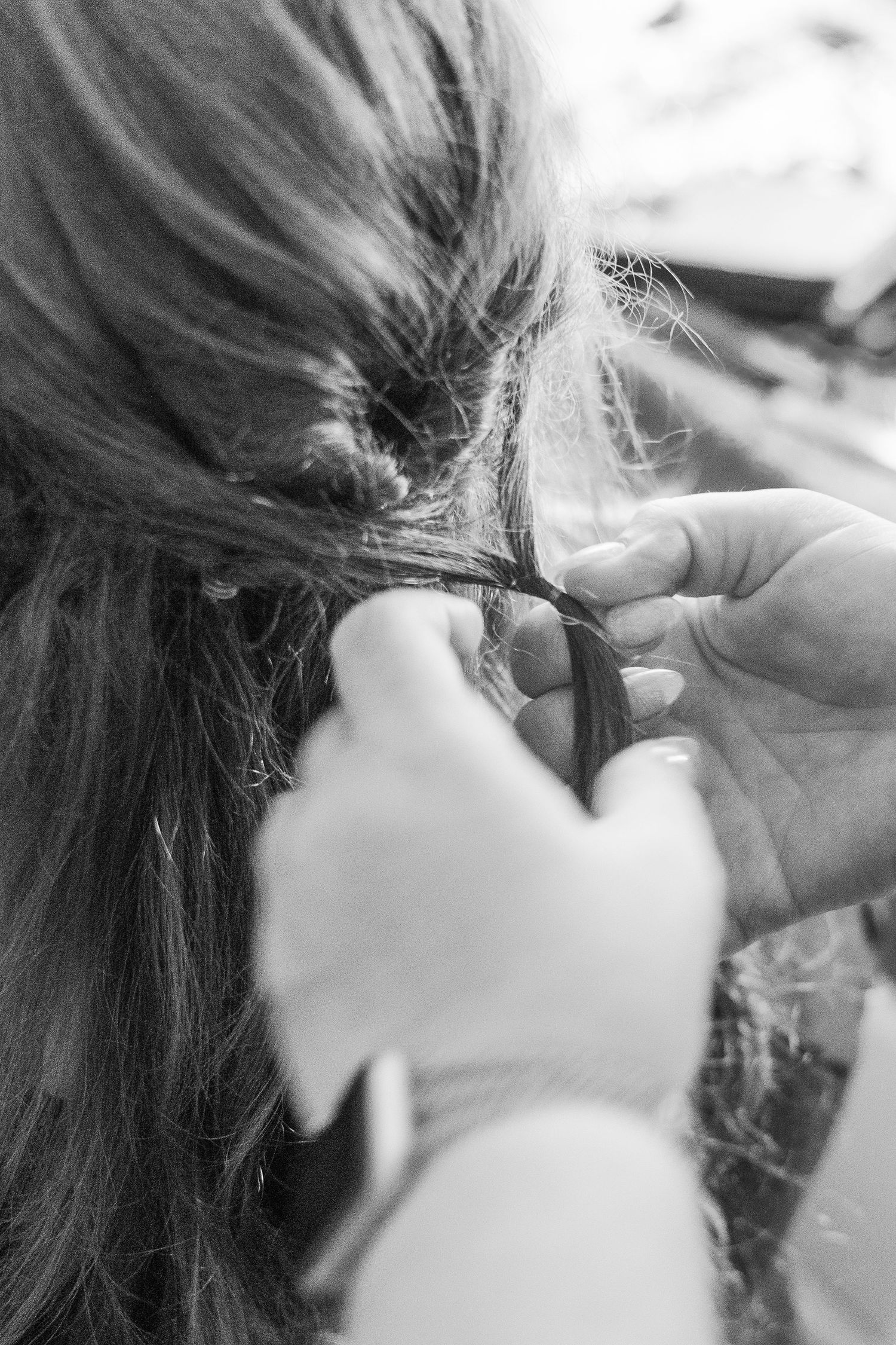 Close-up shot of hands styling long dark hair in black and white.