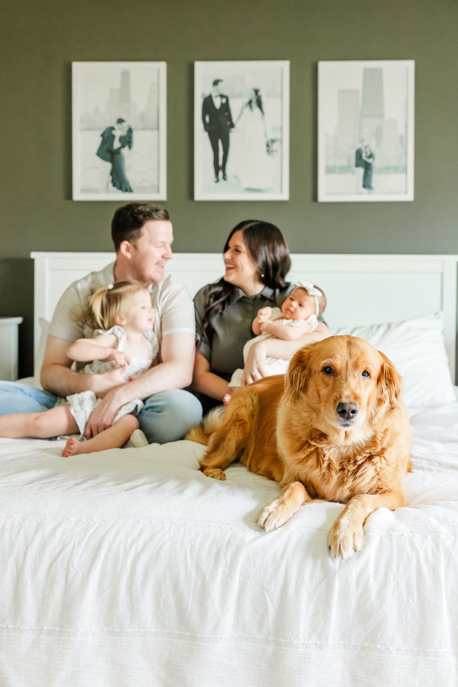 In-home lifestyle newborn session with parents, big sister, newborn baby girl, and golden retriever on the bed in Huntley IL