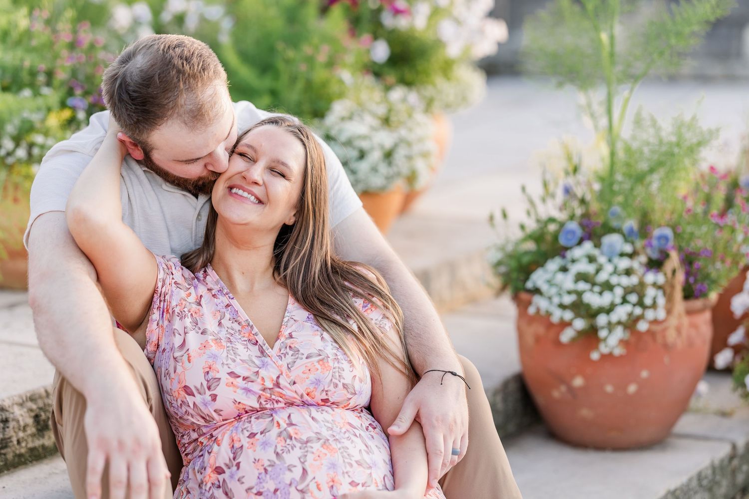 Seated maternity portrait of expecting parents on stone steps at Cantigny Park in Wheaton Illinois summer gardens