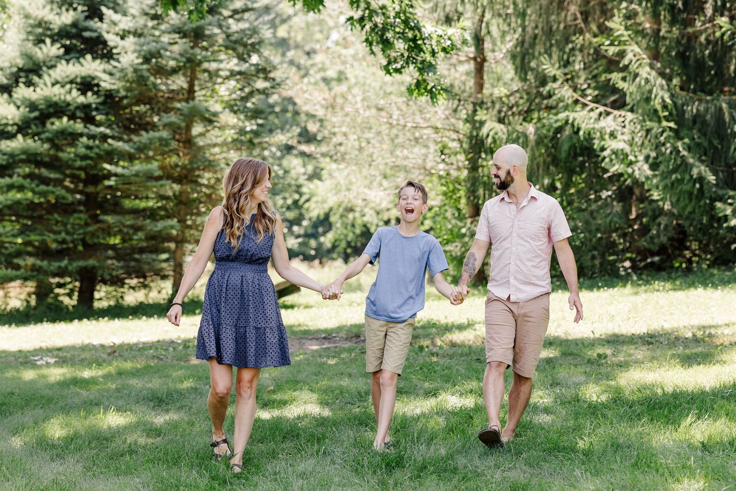 Family walking hand in hand through the yard during a relaxed summer family session in Crystal Lake, Illinois.