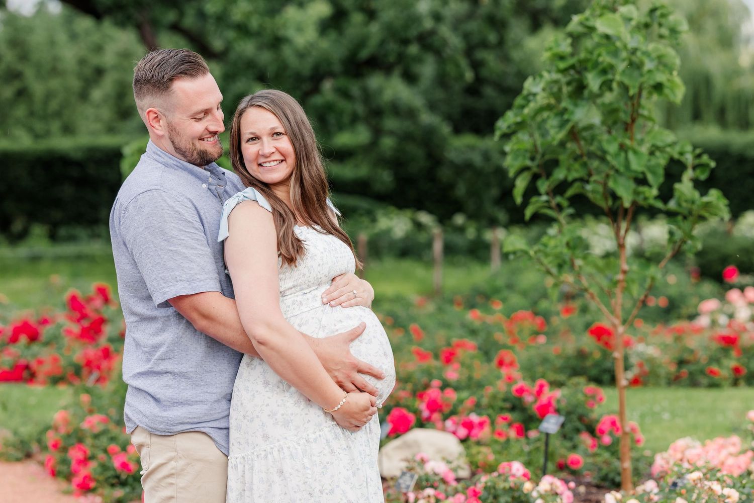 Expecting parents cuddling in colorful flowers during a Cantigny Park maternity session
