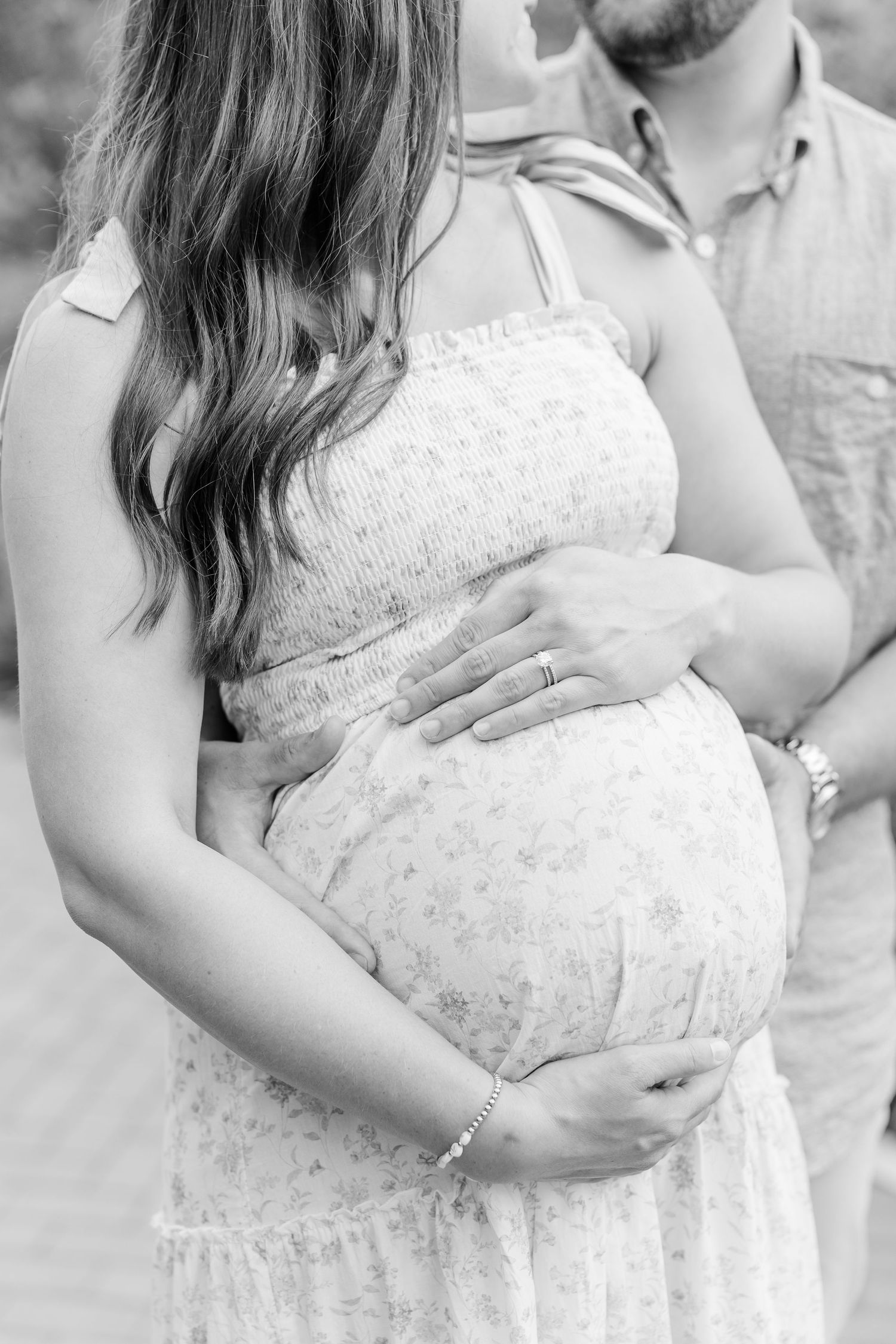 Black and white maternity detail photo of an expecting mother holding her baby bump