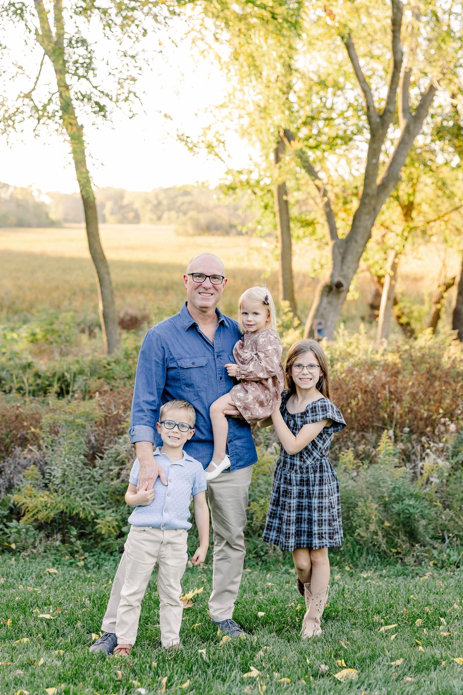 Dad holding his youngest daughter with his two older children beside him in their St. Charles, IL backyard.