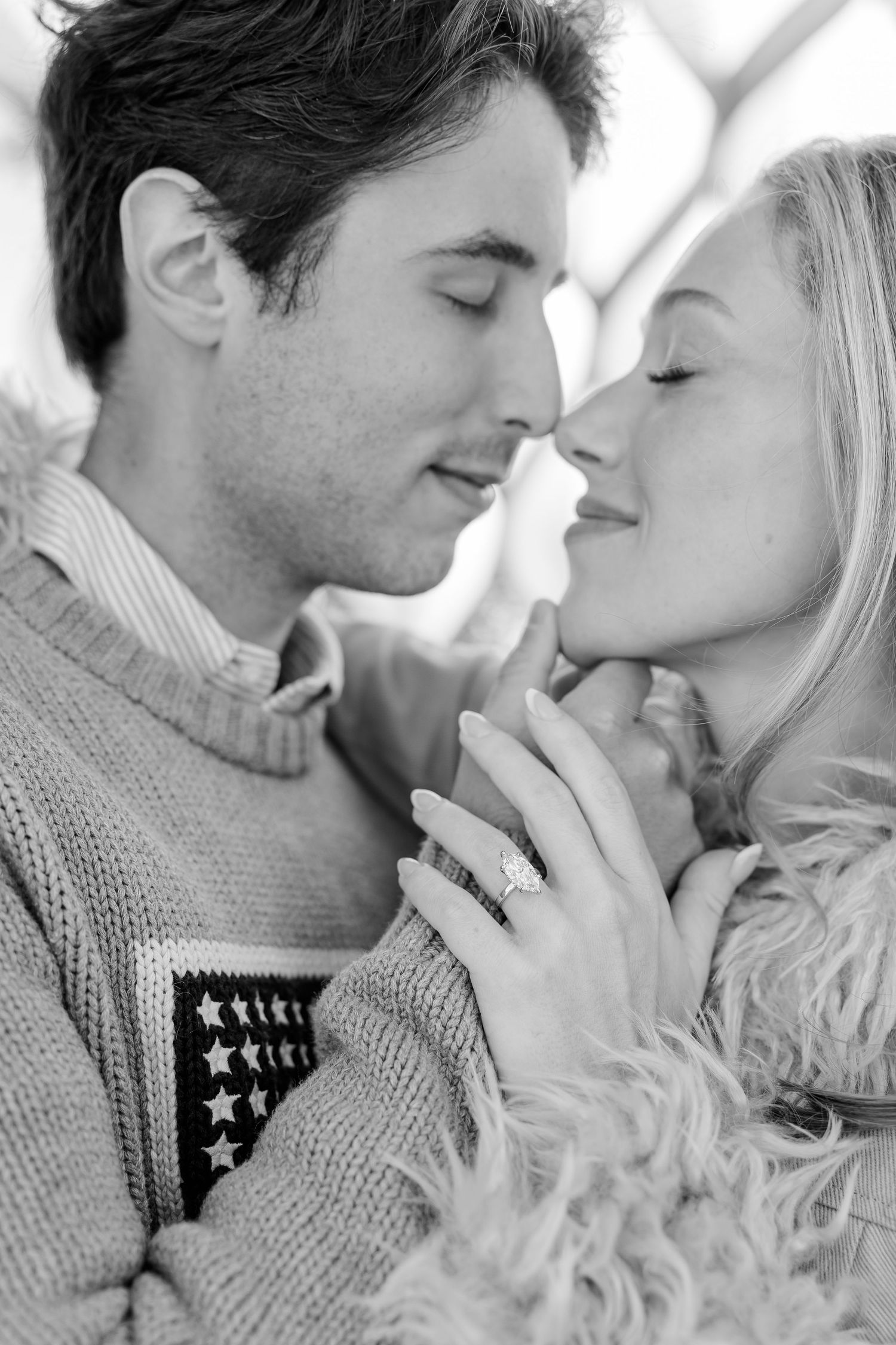 Black and white photo of a romantic couple about to kiss, woman showing off diamond engagement ring.