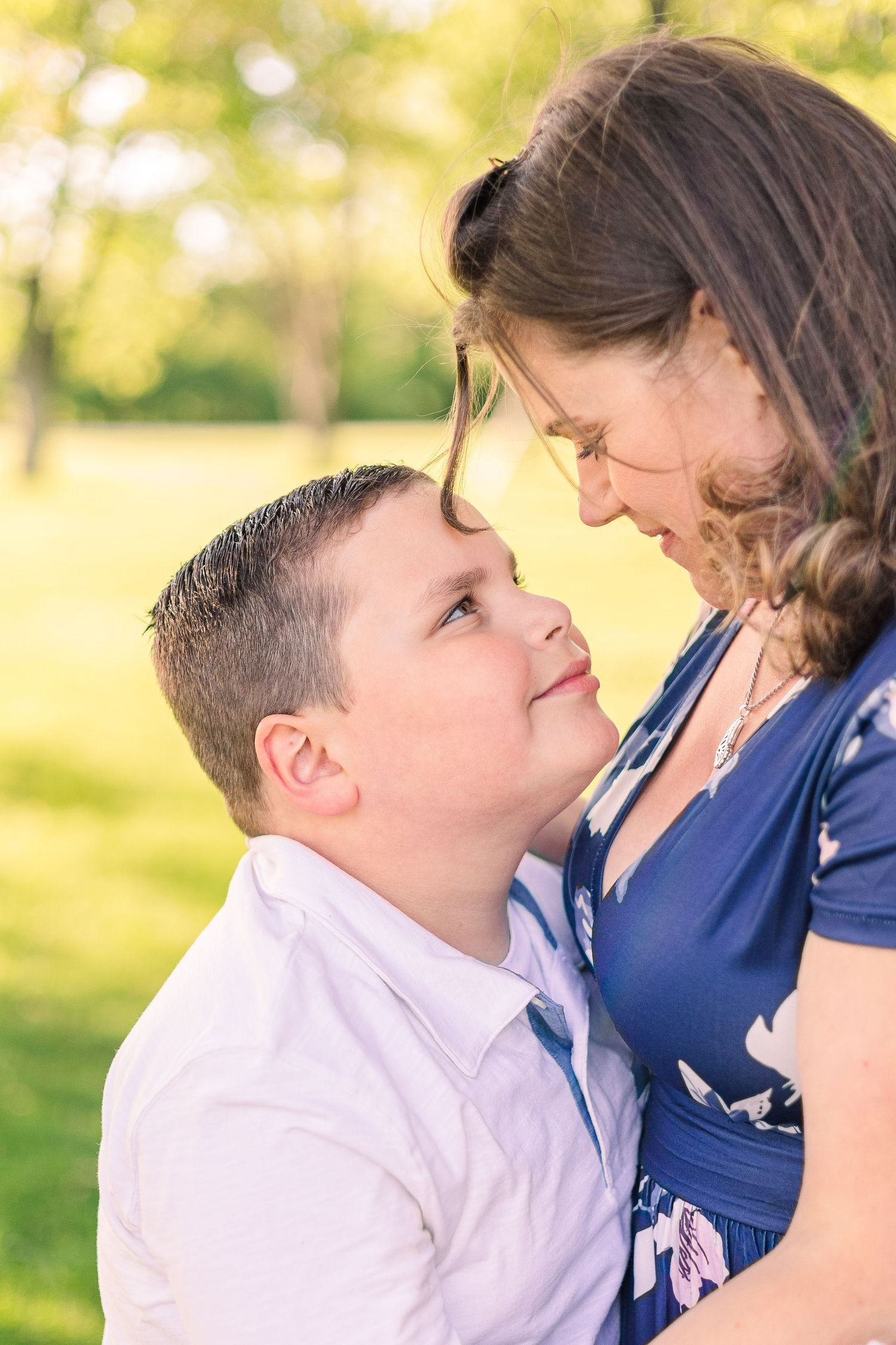 Close-up portrait showing tender interaction between two people in sunlit outdoor setting.