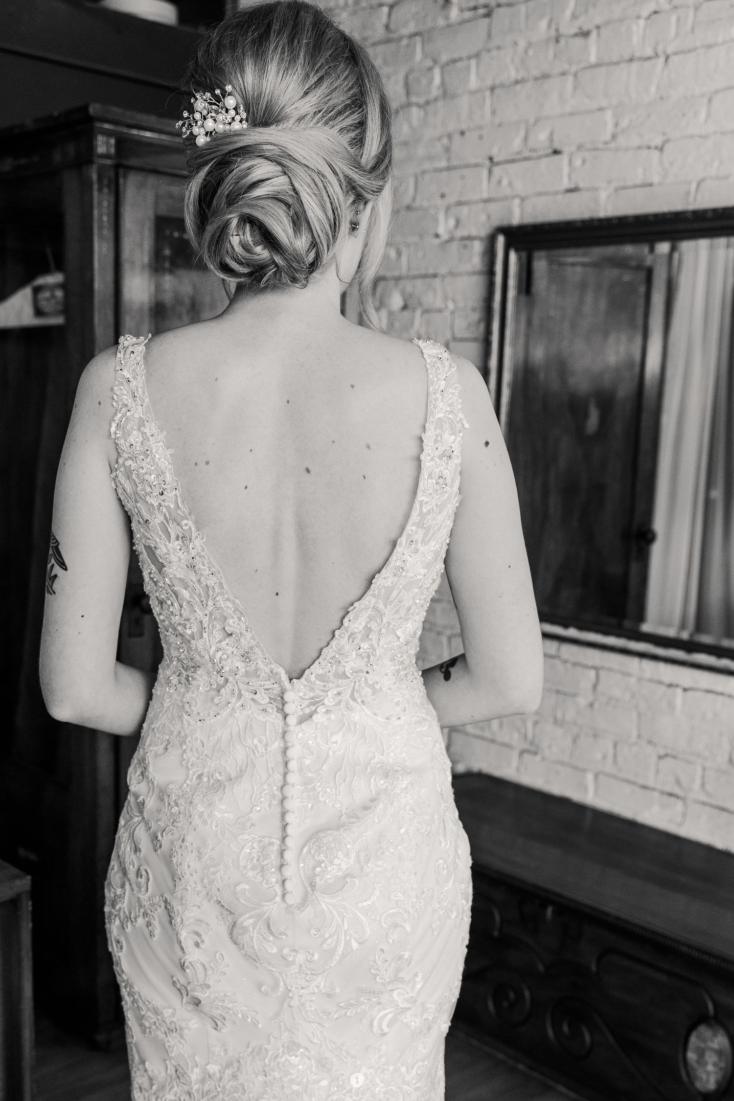 Back view of a lace wedding gown with deep V-cut and elegant updo hairstyle with tiara.