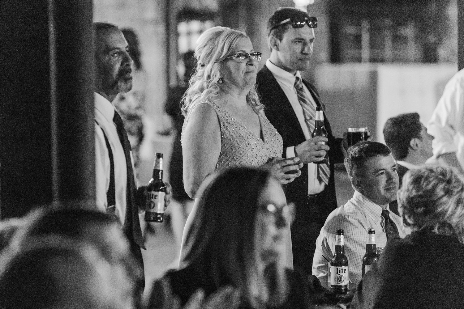 Black and white photo of wedding guests during reception toasts.