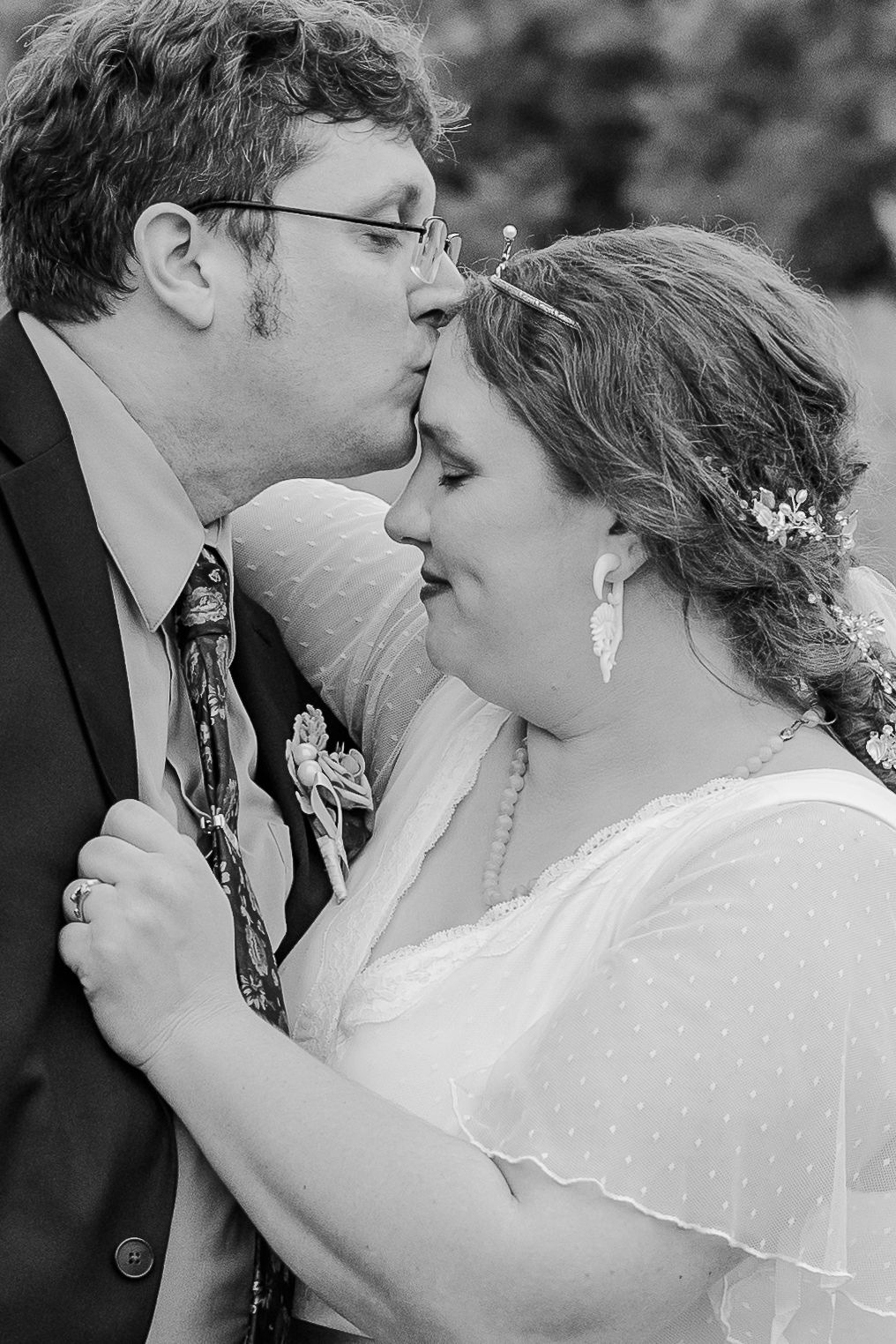 A black and white close-up wedding portrait capturing an intimate moment between the newlyweds.